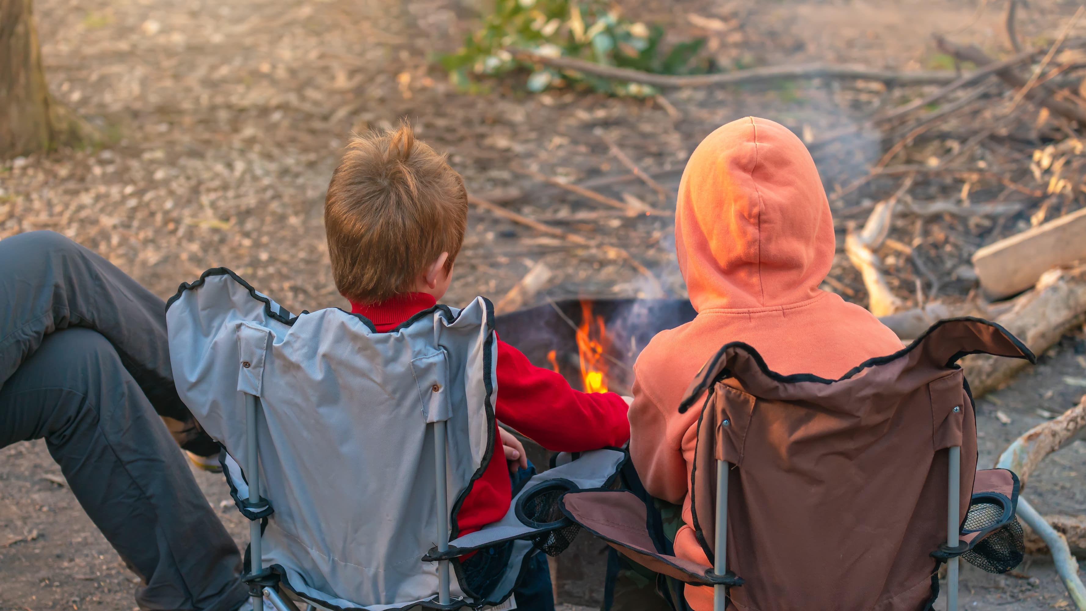 Two kids sitting in front of a campfire