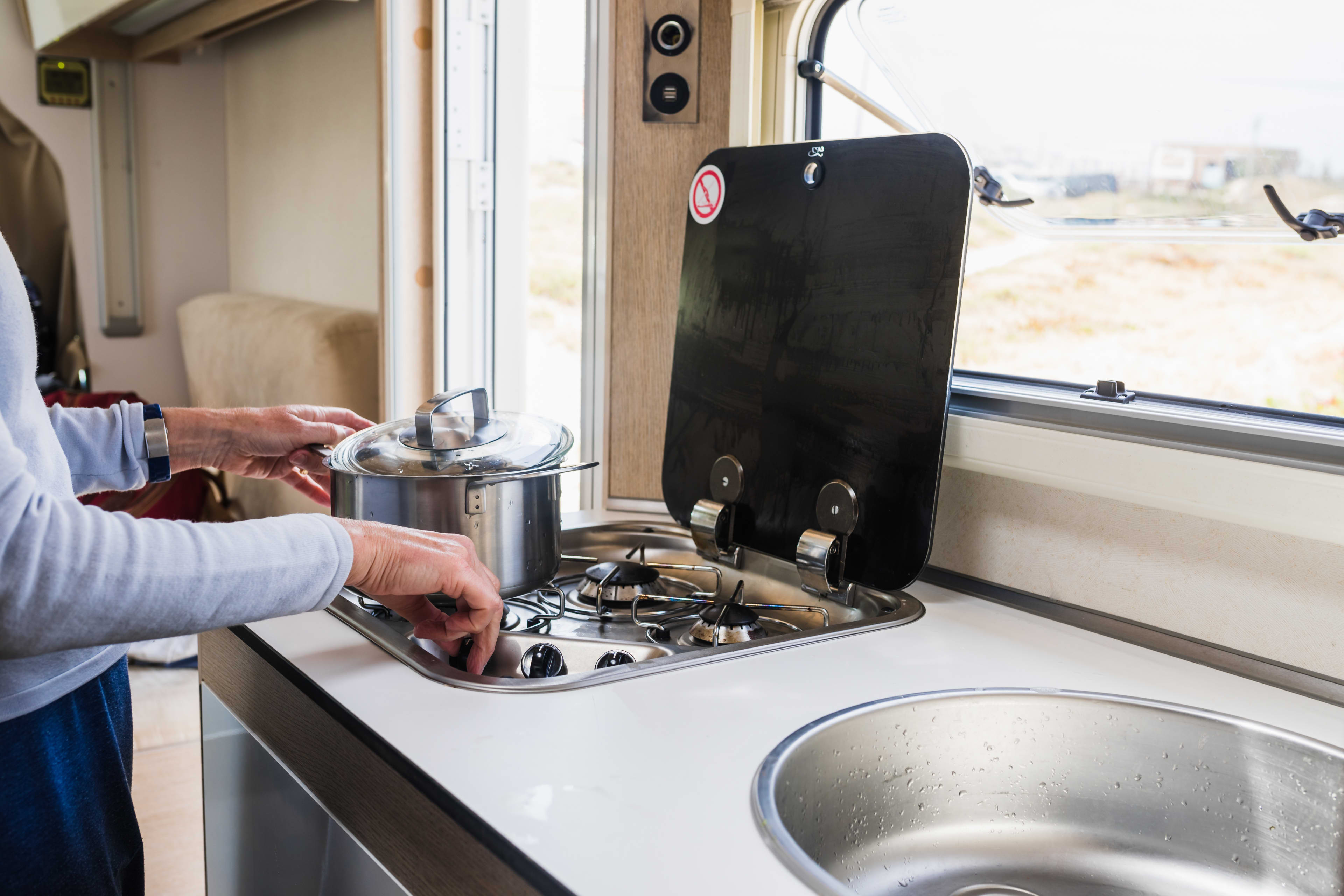 A person cooking on a caravan stove