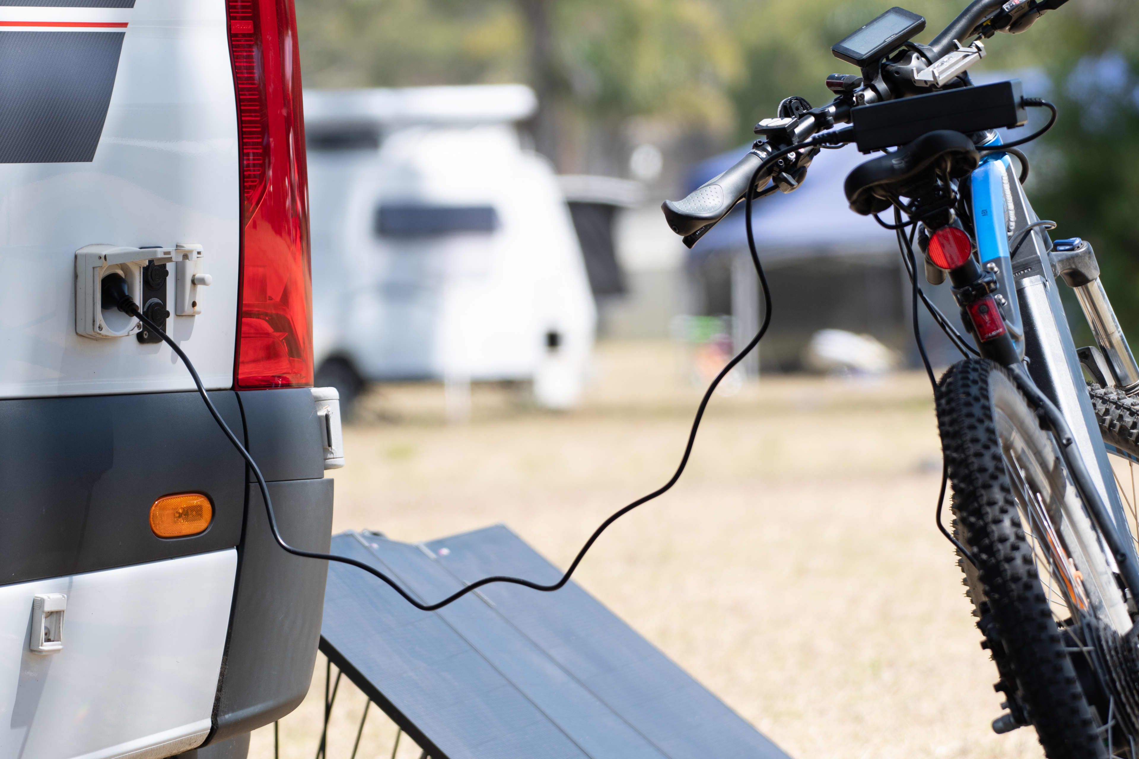 An ebike being charged from the rear of a caravan