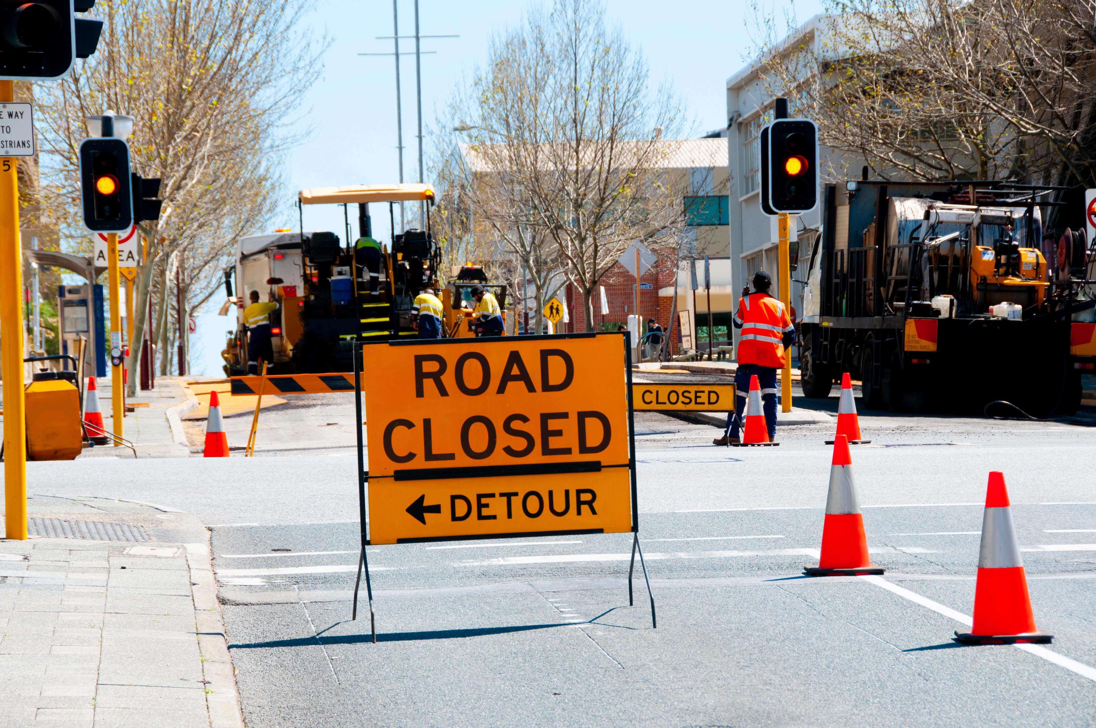 A traffic detour sign on a Perth road with road works taking place in the background