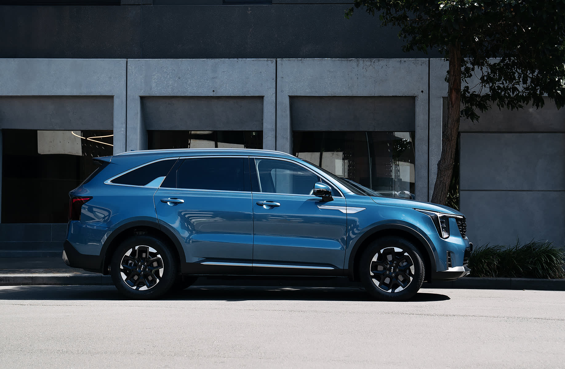 A blue Kia Sorrento parked outside a city building