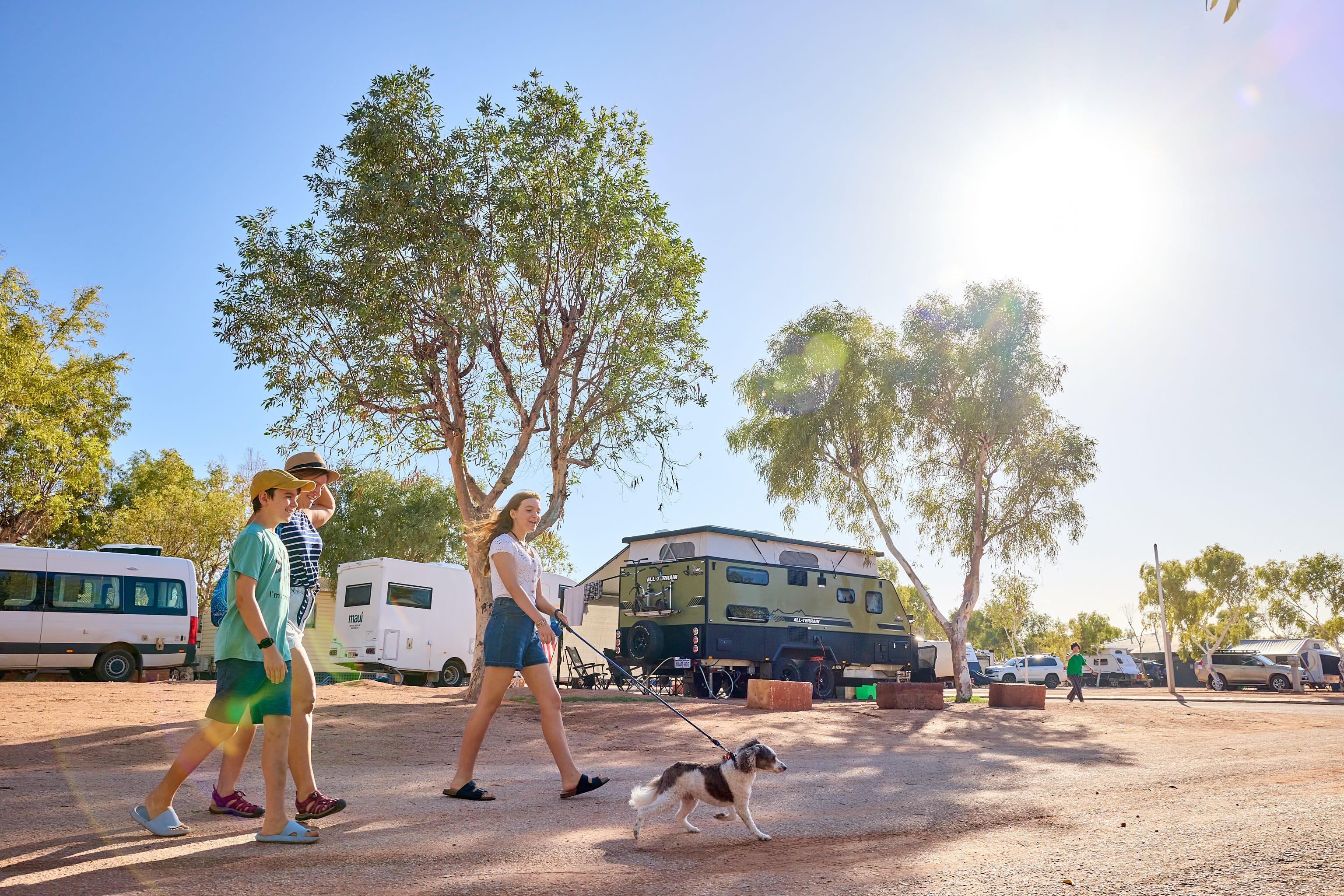 Family walking with dog at RAC Exmouth Cape Holiday Park, caravans and camper trailers in the background