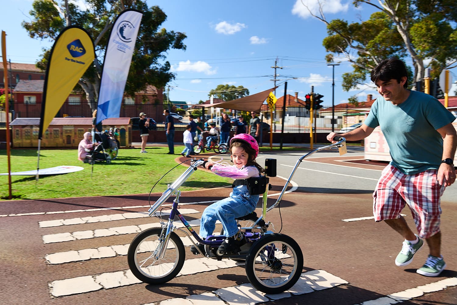 Young child riding her bike with her father pushing the bike from behind.