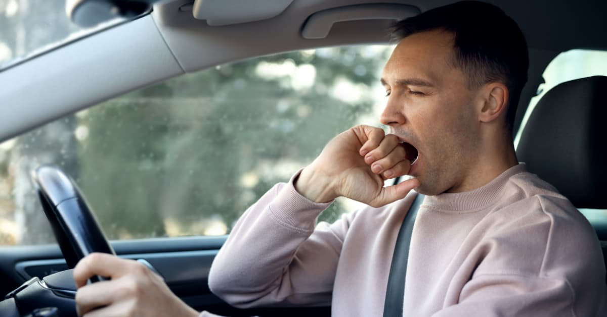Man yawning while driving car