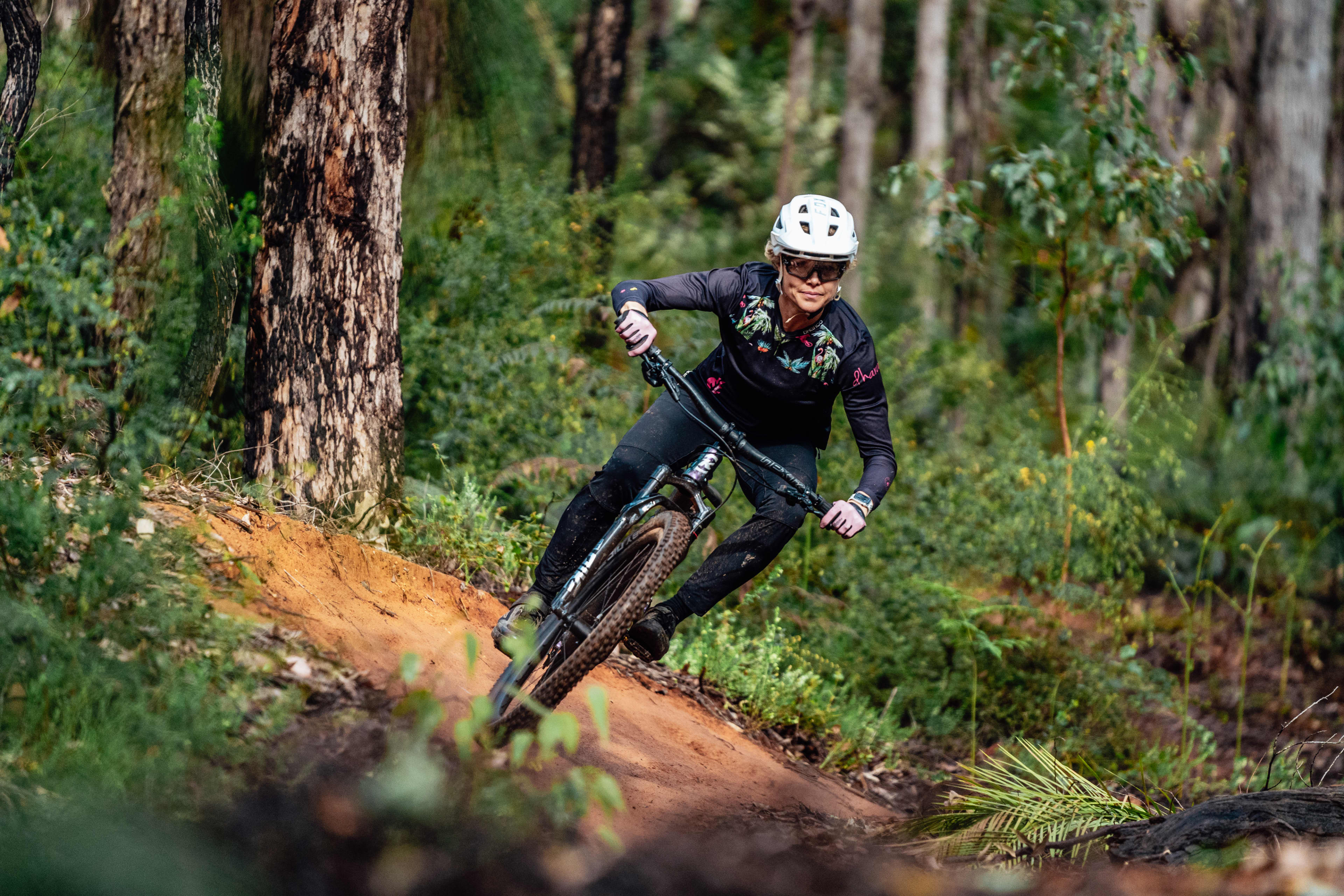Person up close riding mountain bike down hill in forest