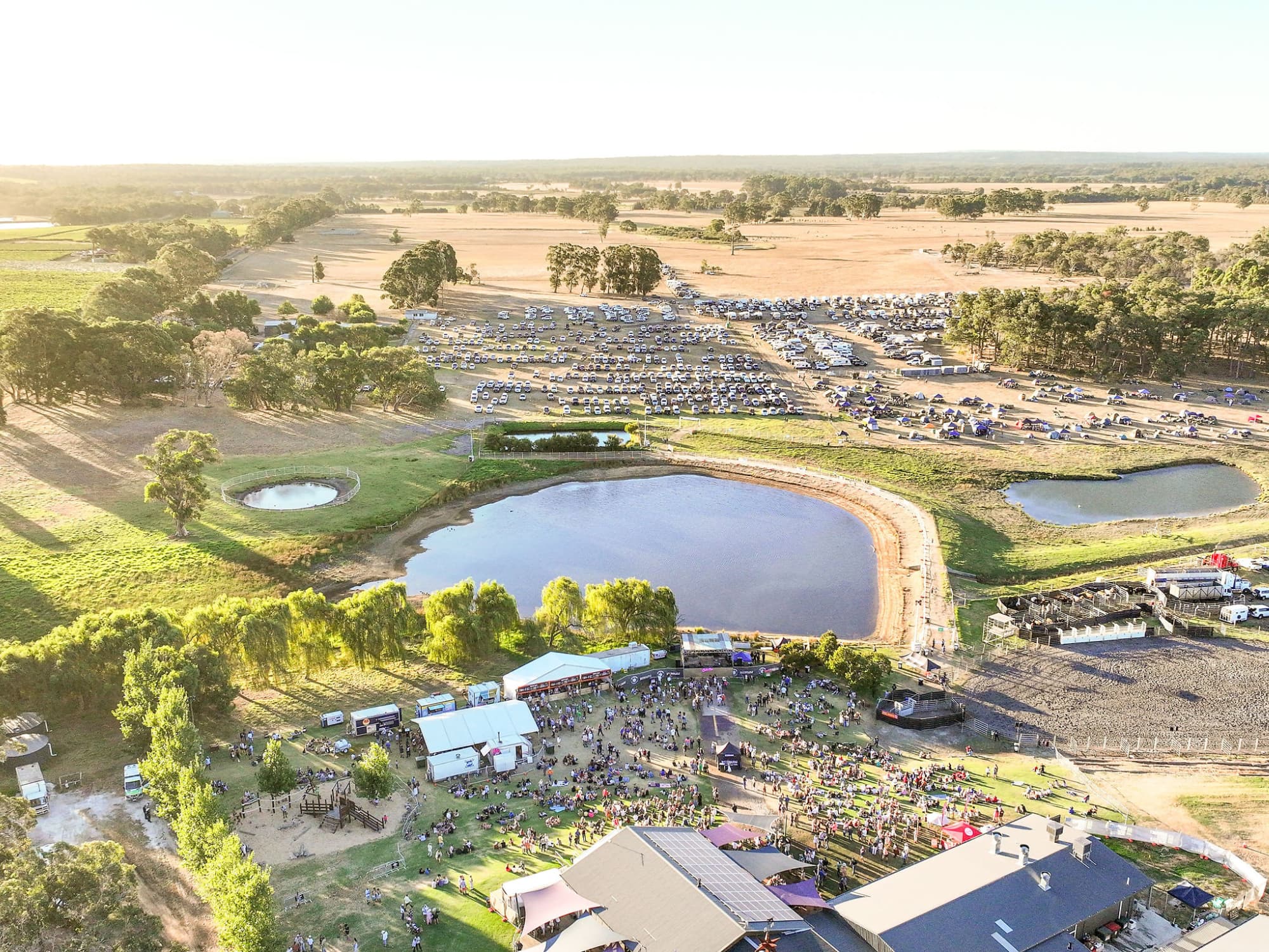 Aerial view of large dam and green hills and farmland with event taking place