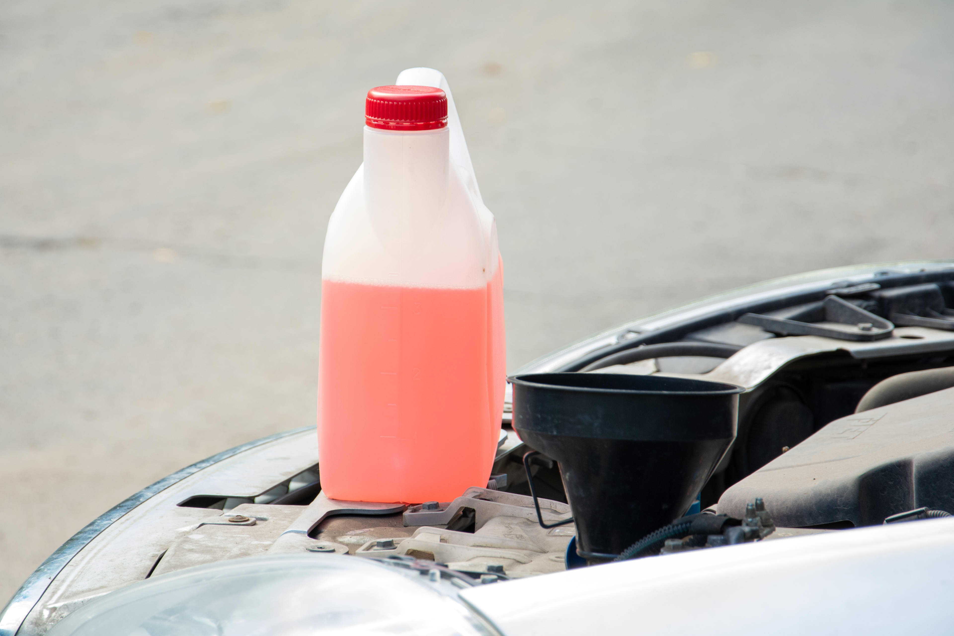 A bottle of brake fluid sitting on the edge of a car engine bay