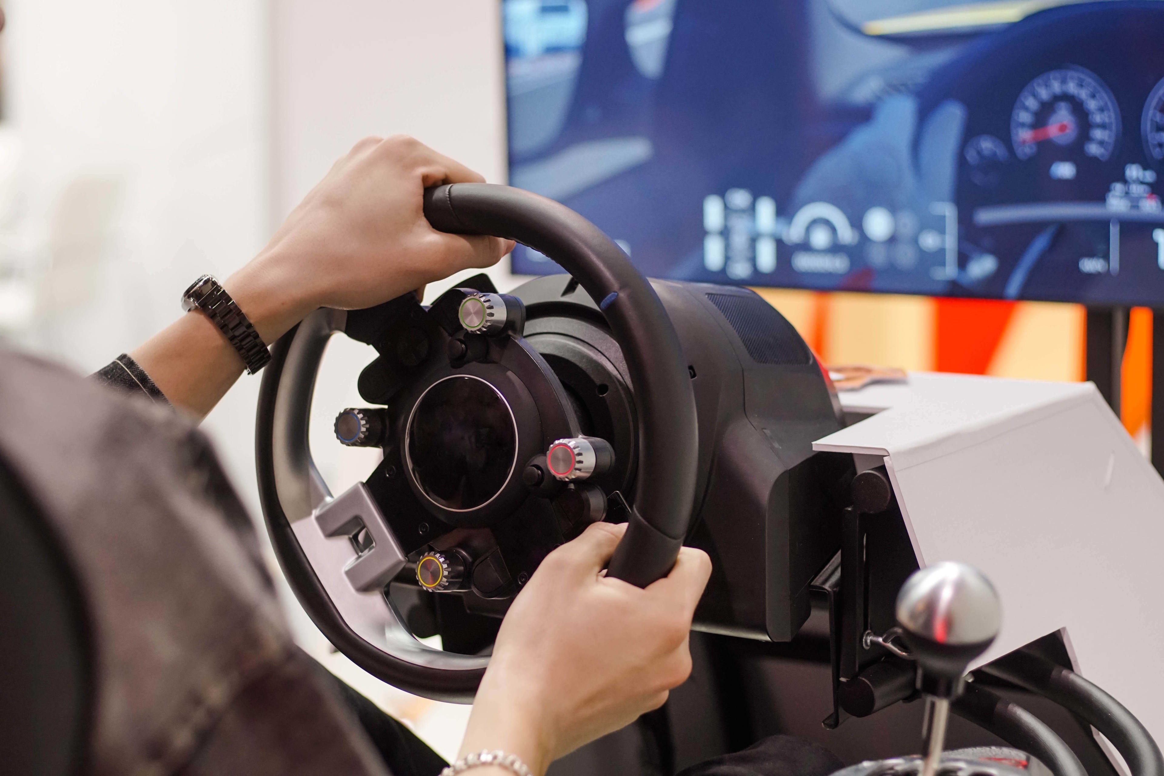 A person's hands on a driving simulator's steering wheel
