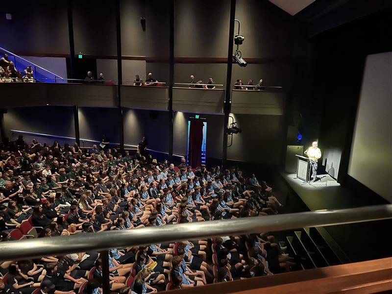 Auditorium full of students listening to a presenter speak.