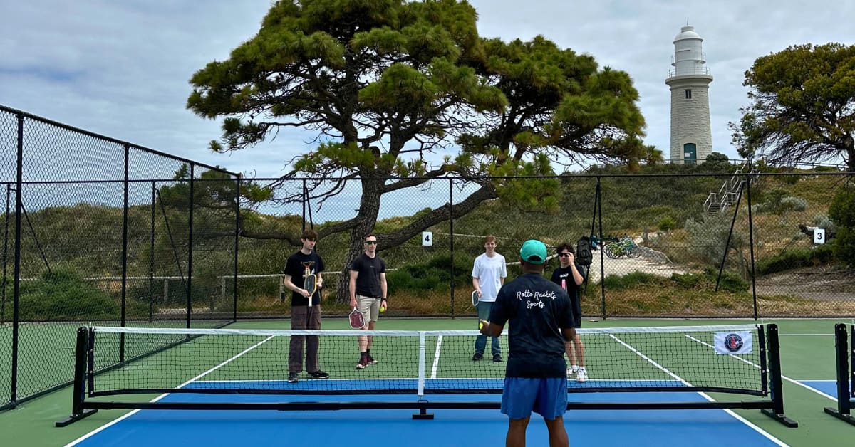 Group of young people learning how to play pickleball on courts