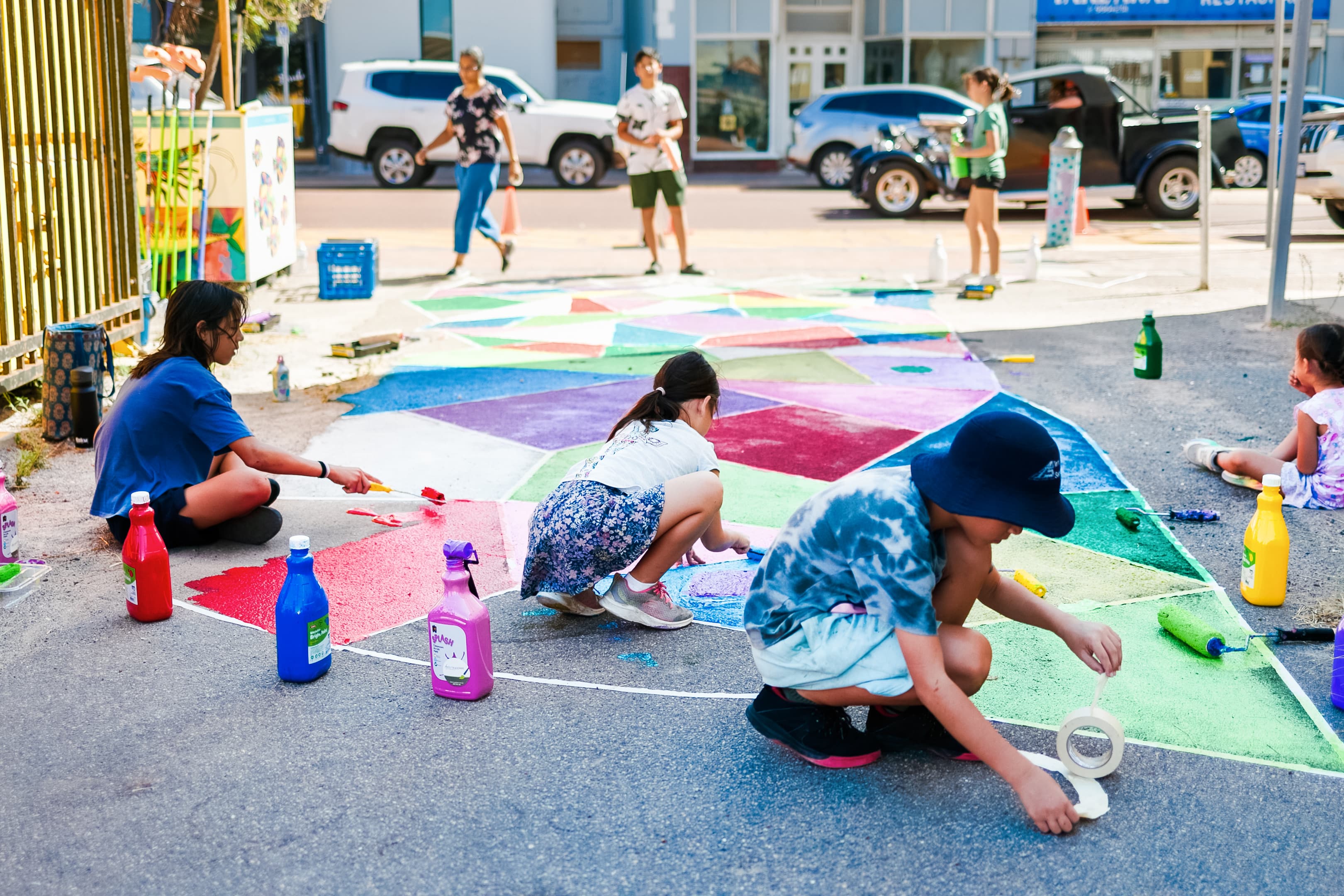 Children painting a colourful mural on a concrete floor