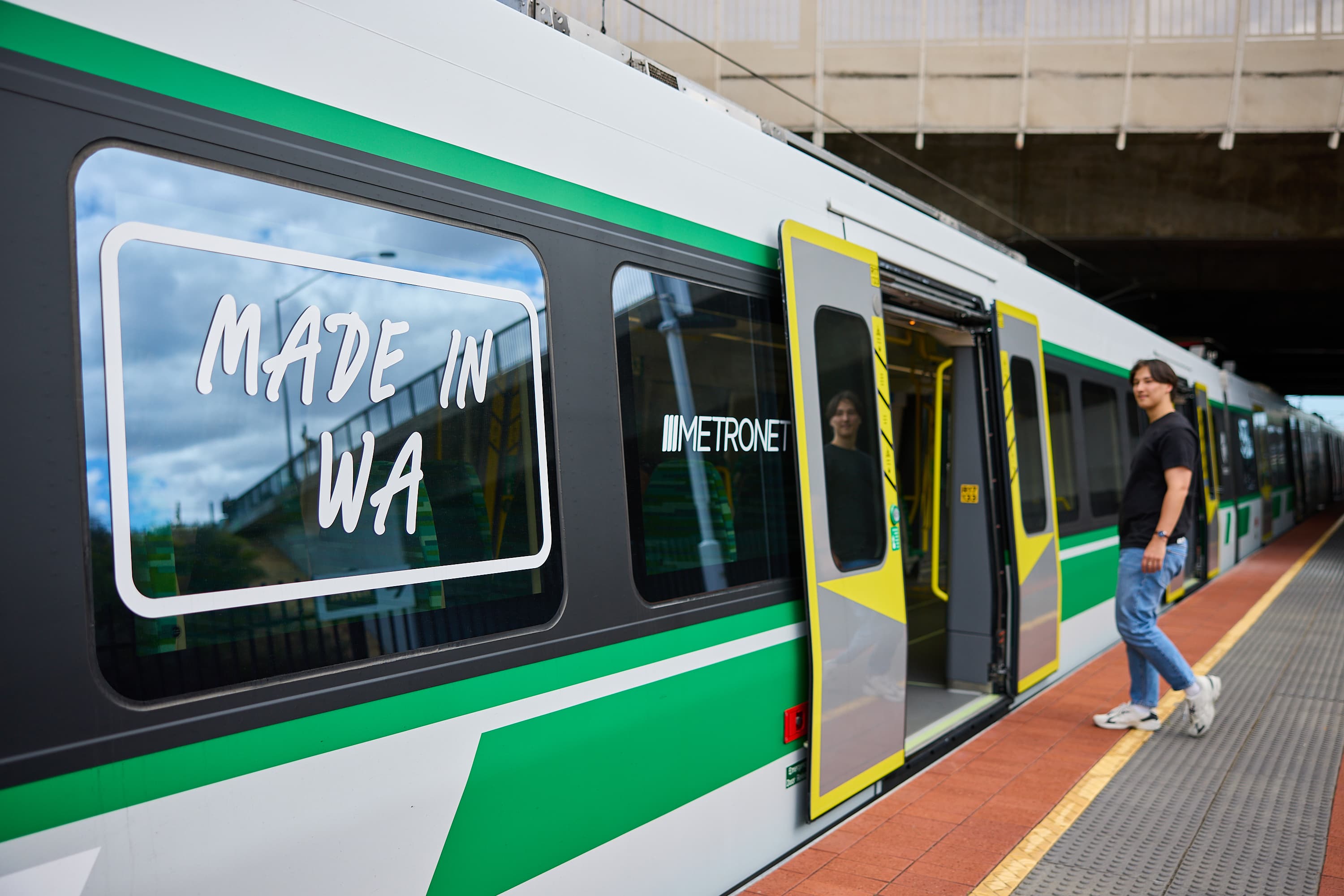 Man walking onto transperth train stopped at platform.