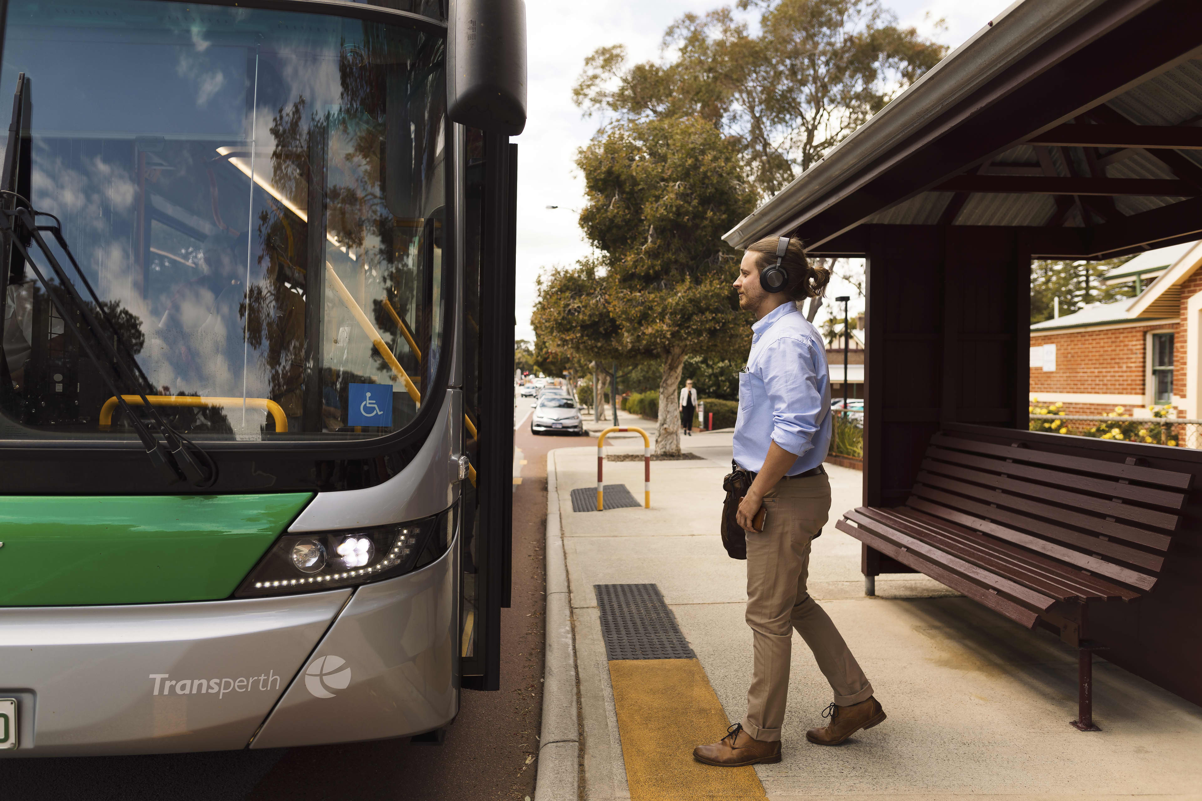 Commuter safely boarding transperth bus stationed at bus stop.