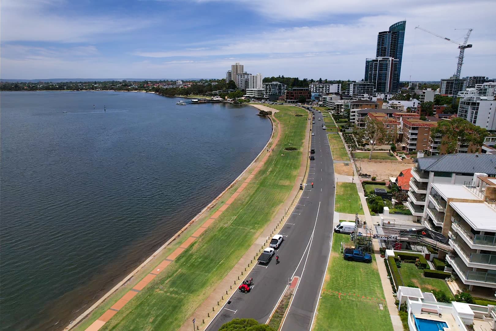 Aerial view of a city landscape showing a long road running parallel to a river.