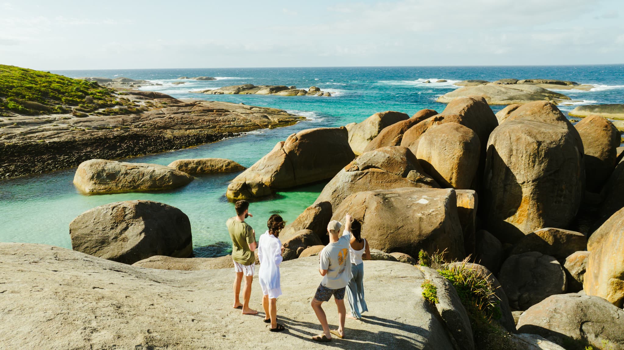 people standing on rocks at Elephants Rocks overlooking turquoise water