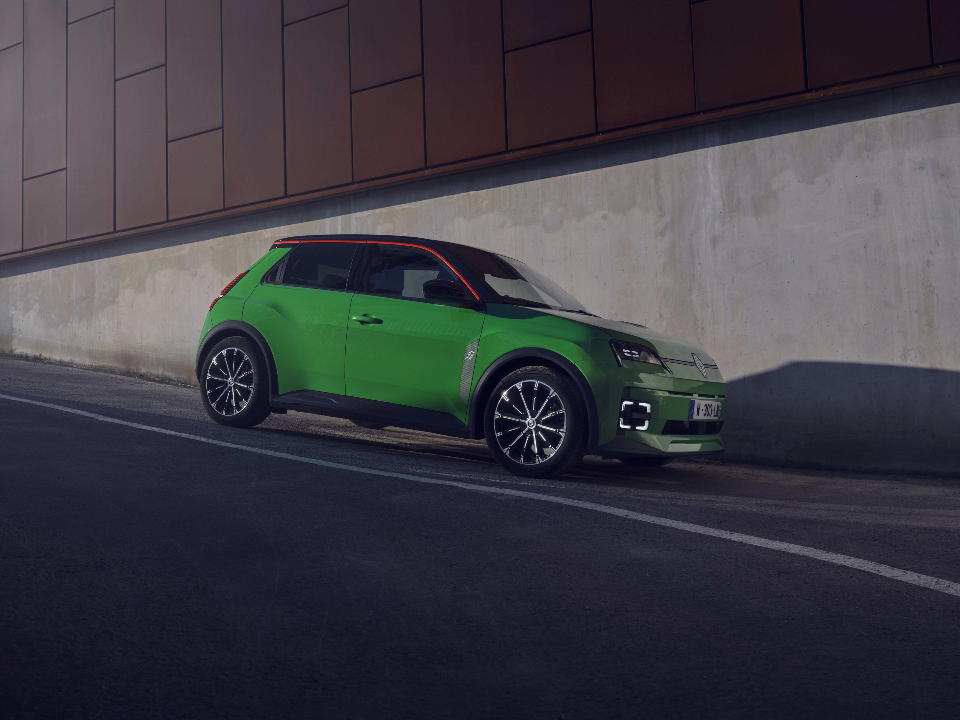 A green Renault EV parked on a city hillside