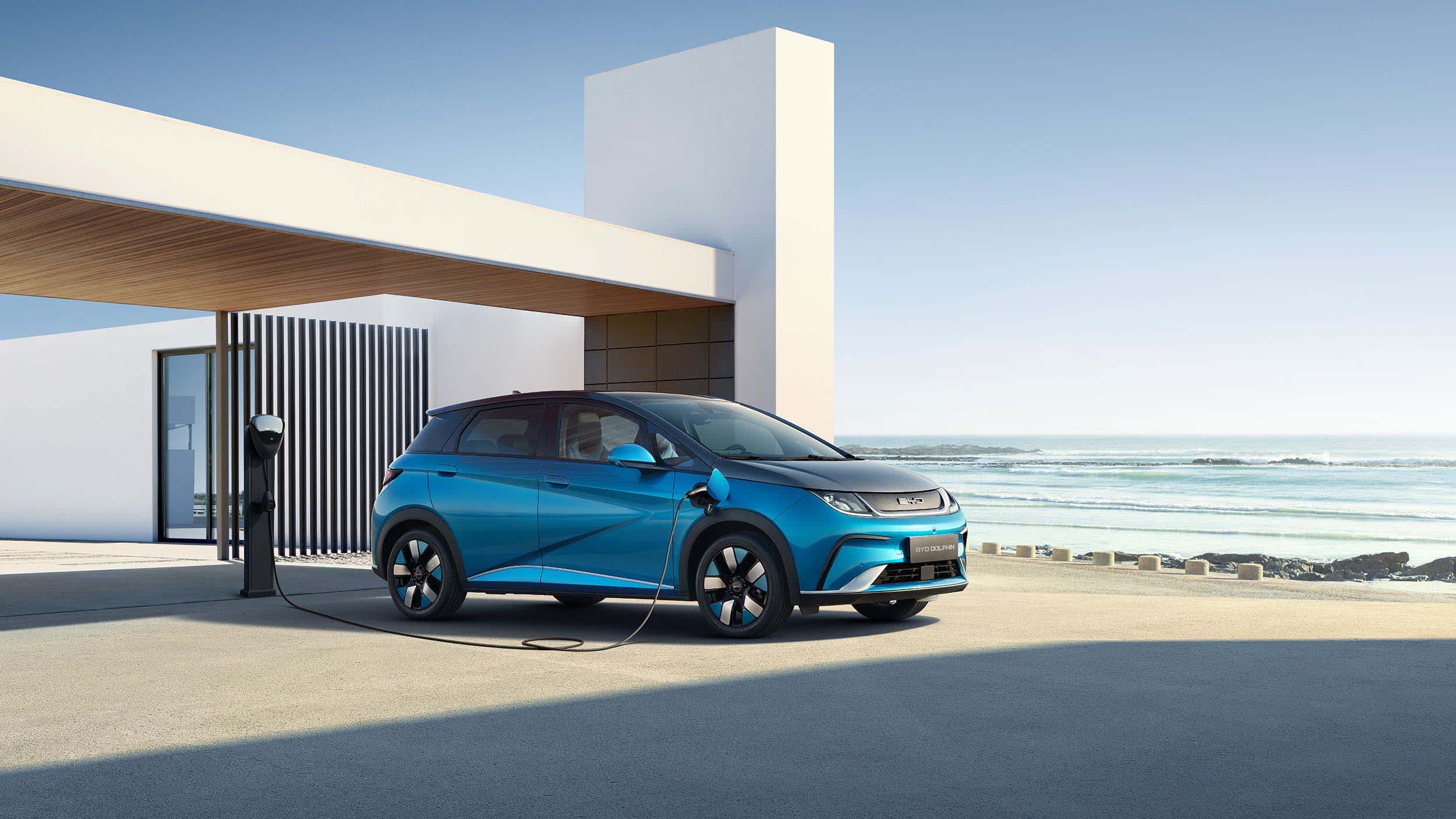 A blue BYD_Dolphin parked near the beach