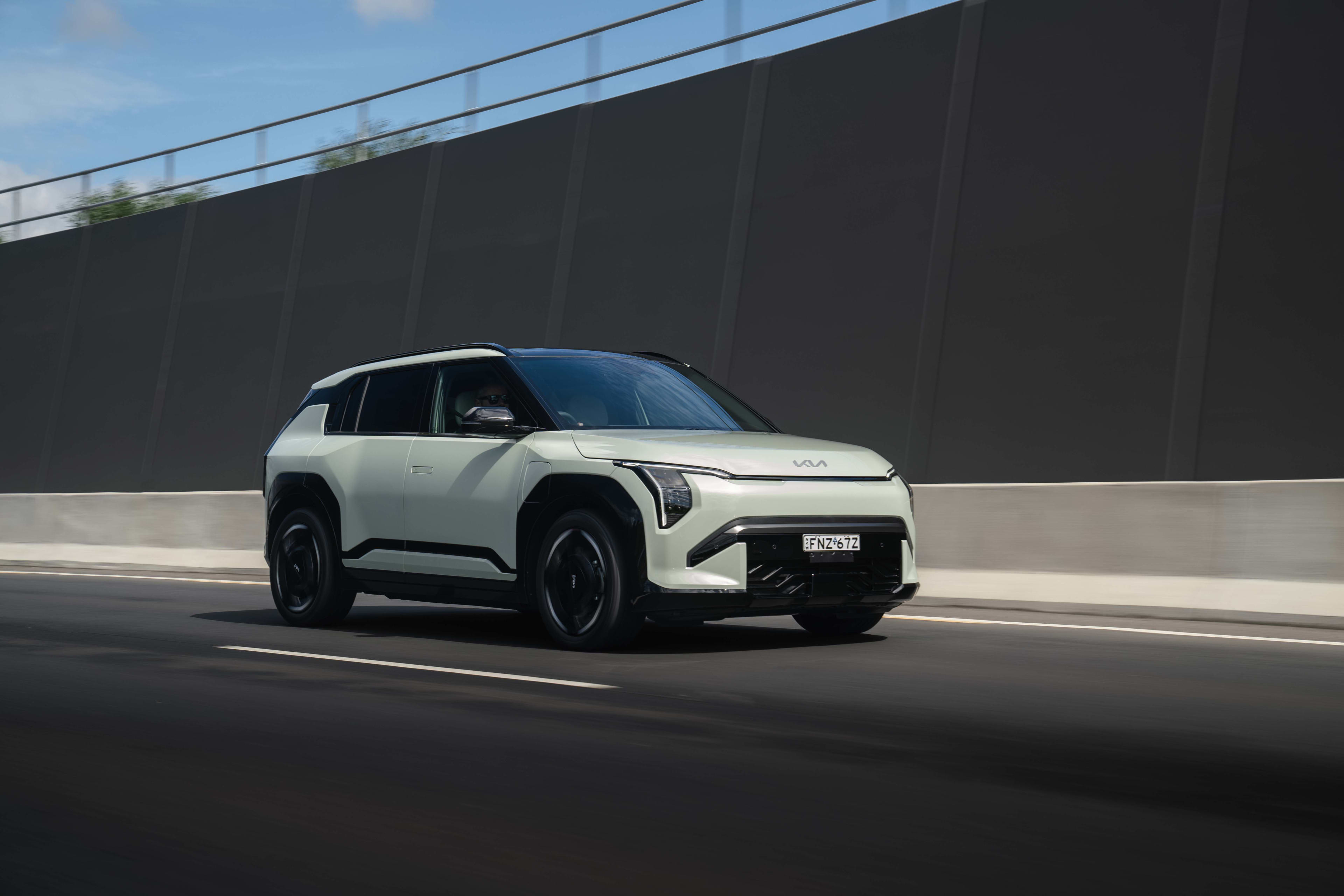 A light green Kia_EV3 on a highway