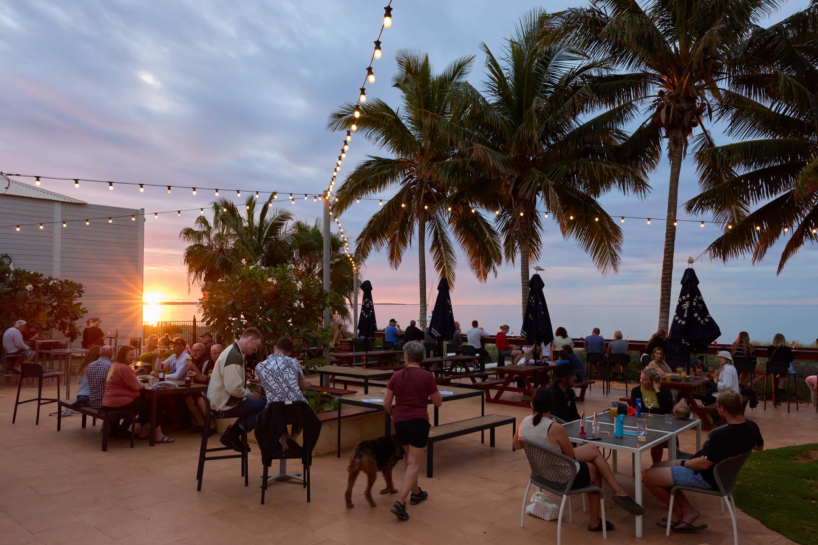 People dining at outdoor tables by the beach