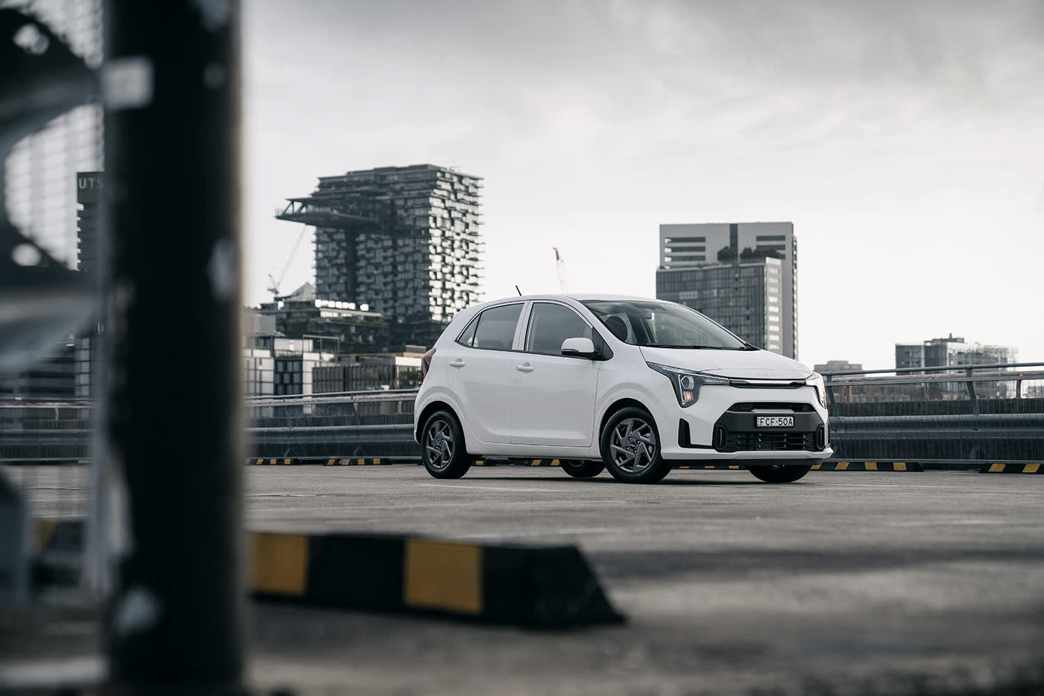 A white Kia_picanto_s on a city overpass