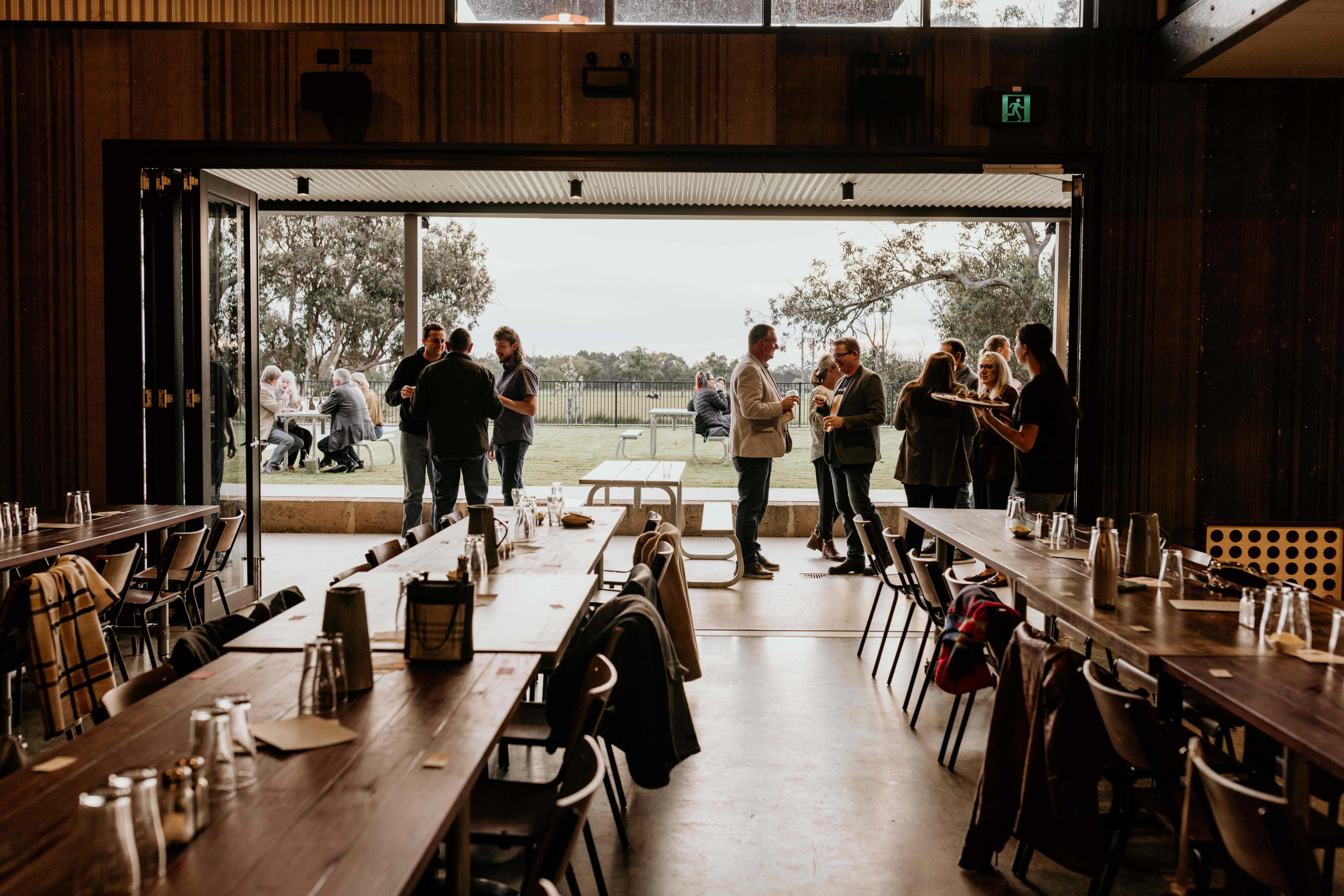 Long tables inside Brugan Brewery with people standing near an open window