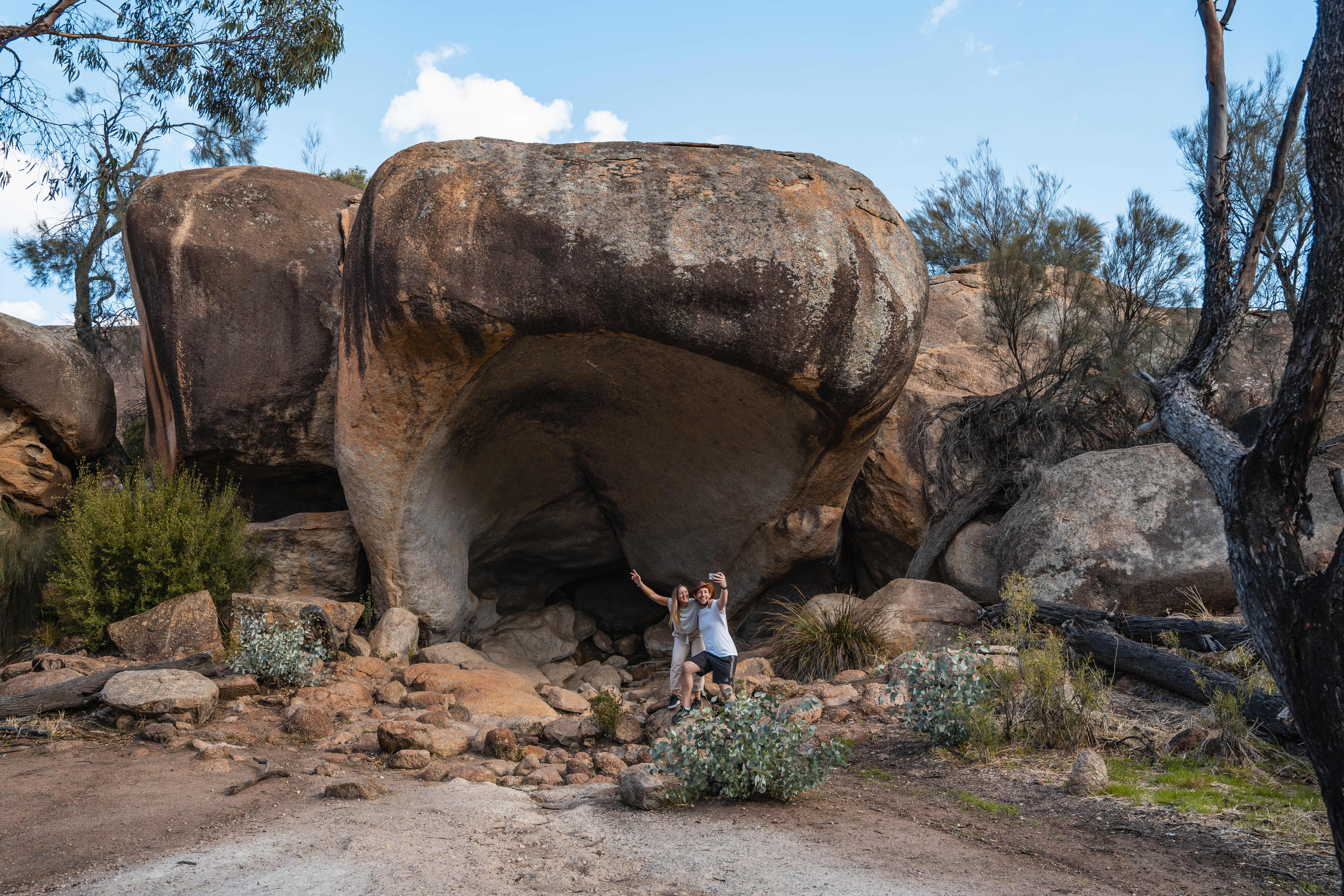 A large granite outcrop resembling the shape of a hippo yawning, with two people posing in front for a photo.