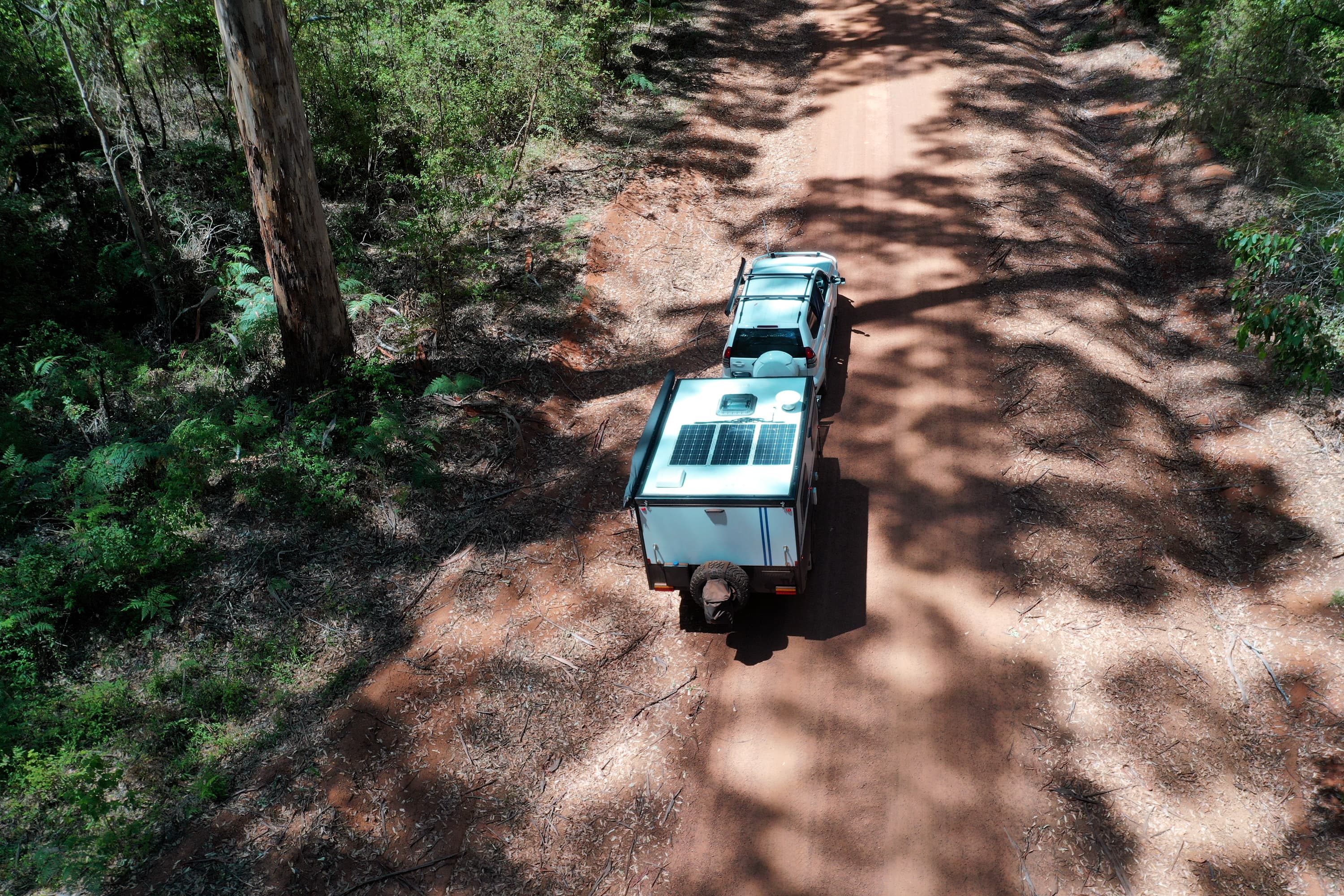 An aerial view of a caravan being towed down a dirt road