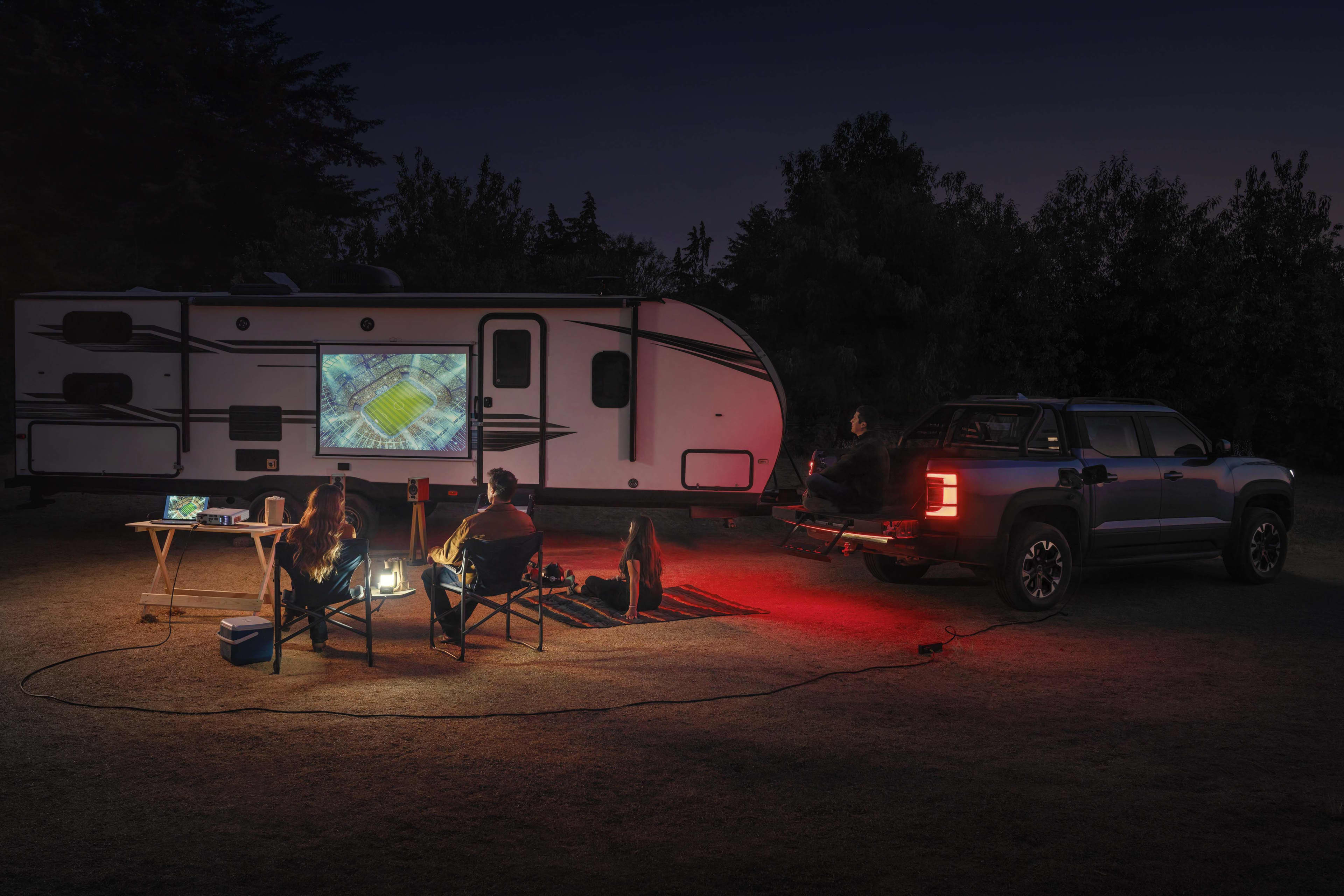 A BYD Shark 6 attached to a caravan in a park at night