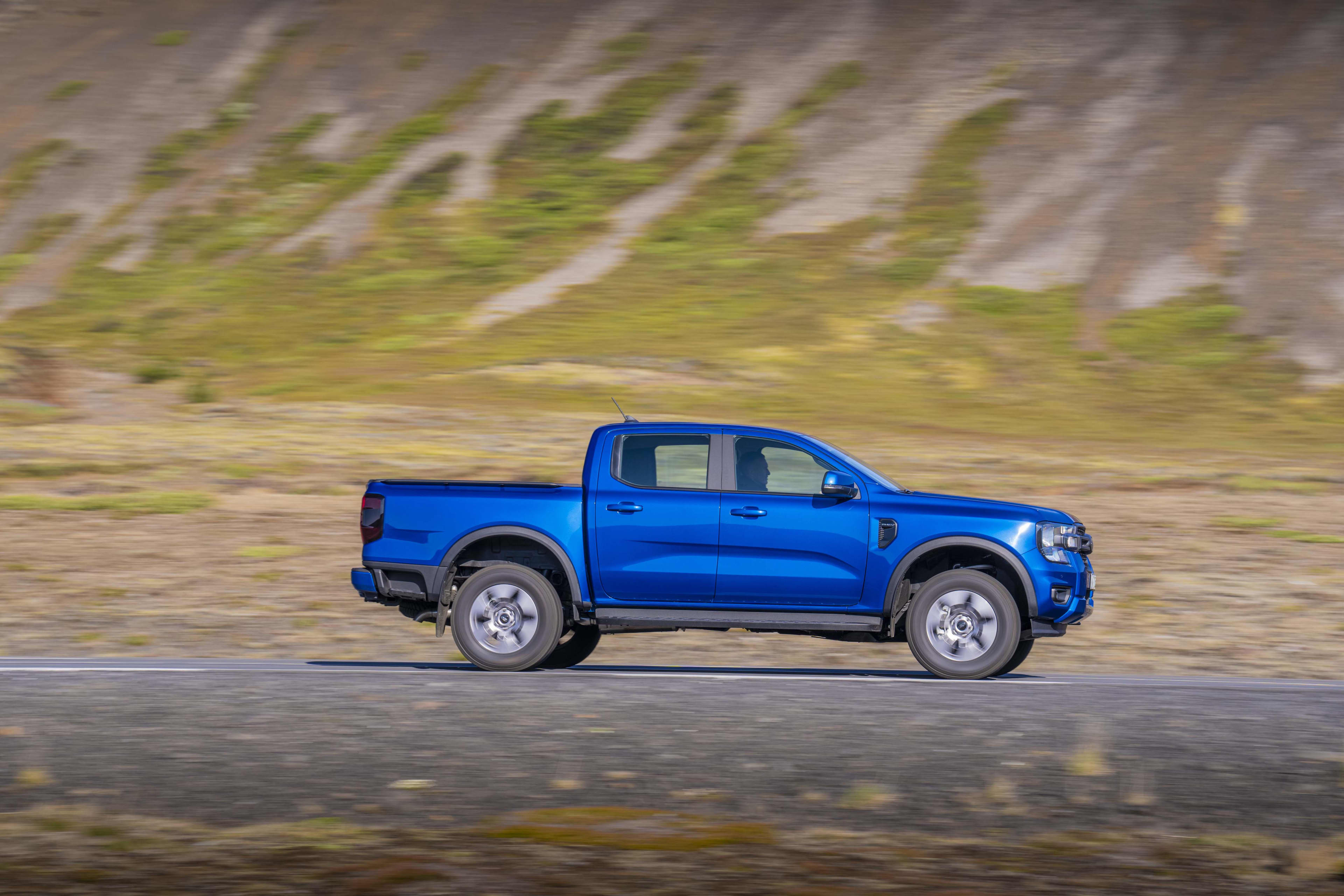 A blue Ford Ranger XLT PHEV driving on a country road