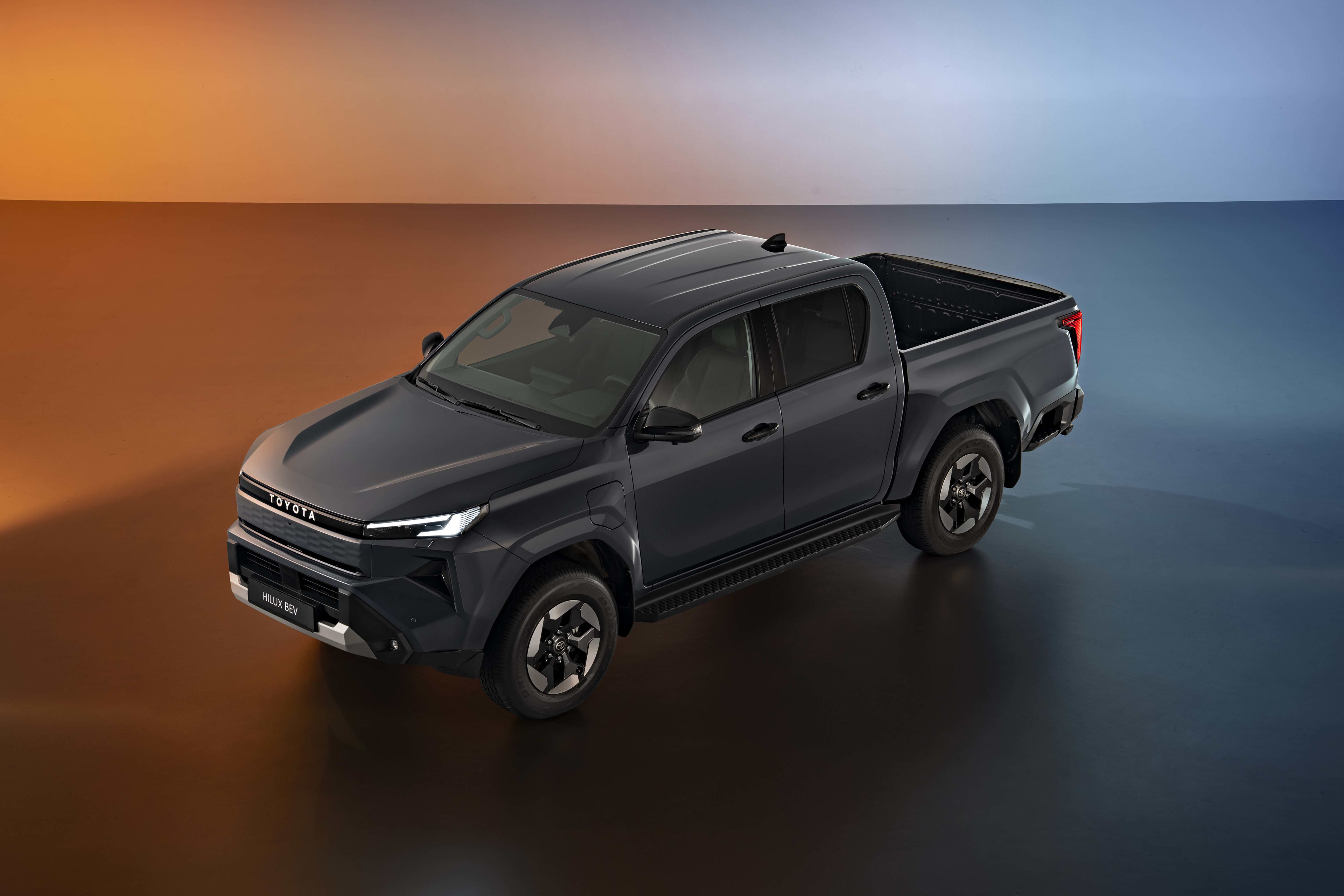 A black Toyota Hilux EV in a studio environment