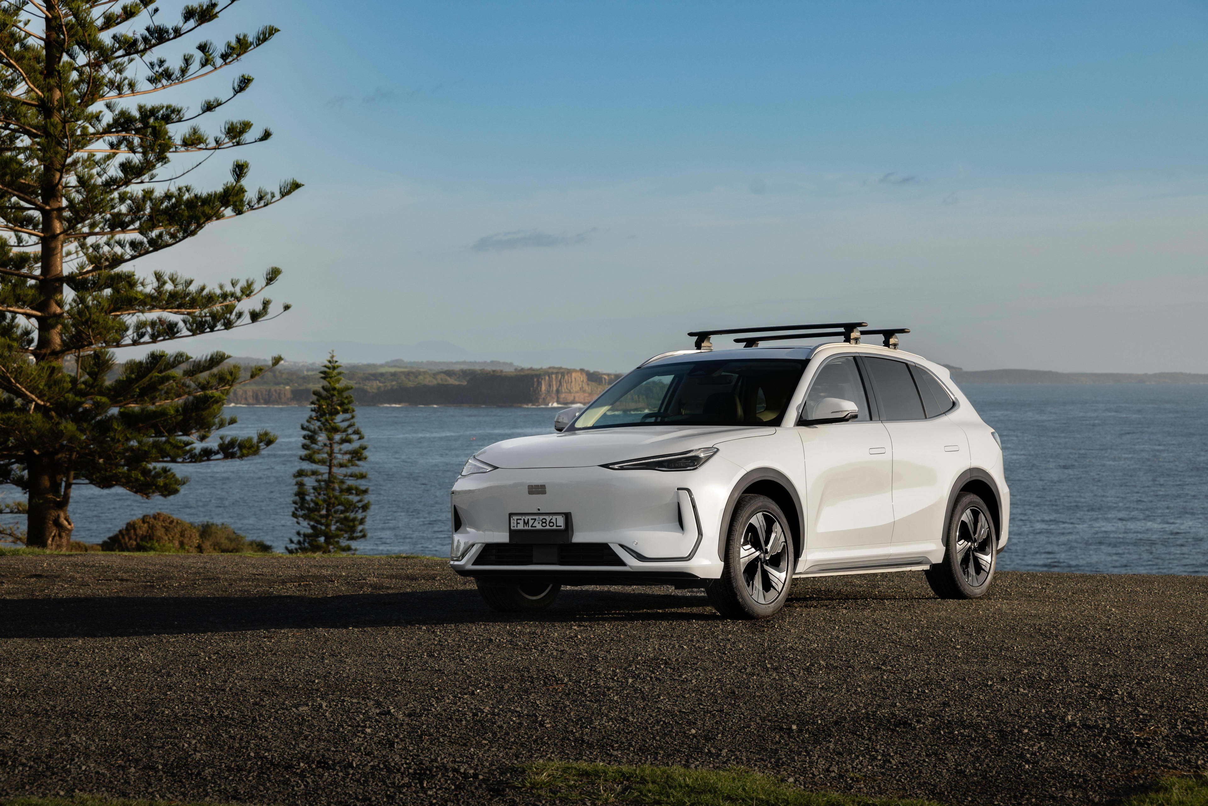 A white Geely EX5 parked near a lake