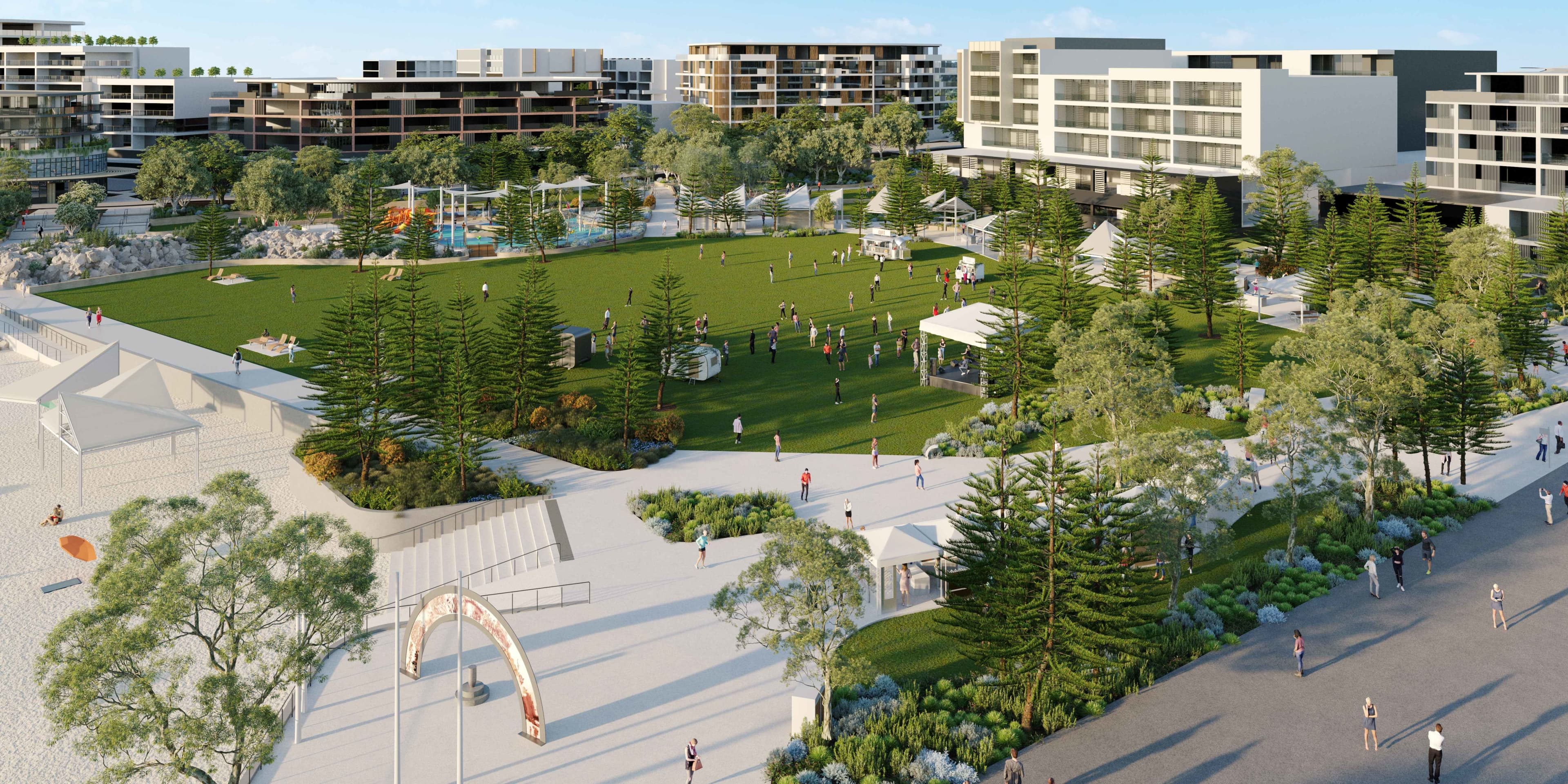 Aerial view of a vibrant park with a central green lawn, surrounded by trees and modern buildings. People enjoy various activities under a clear blue sky.
