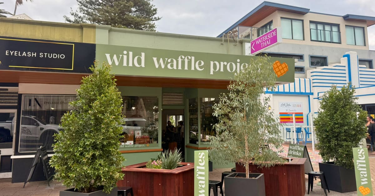 Little green shop with sign and plants.