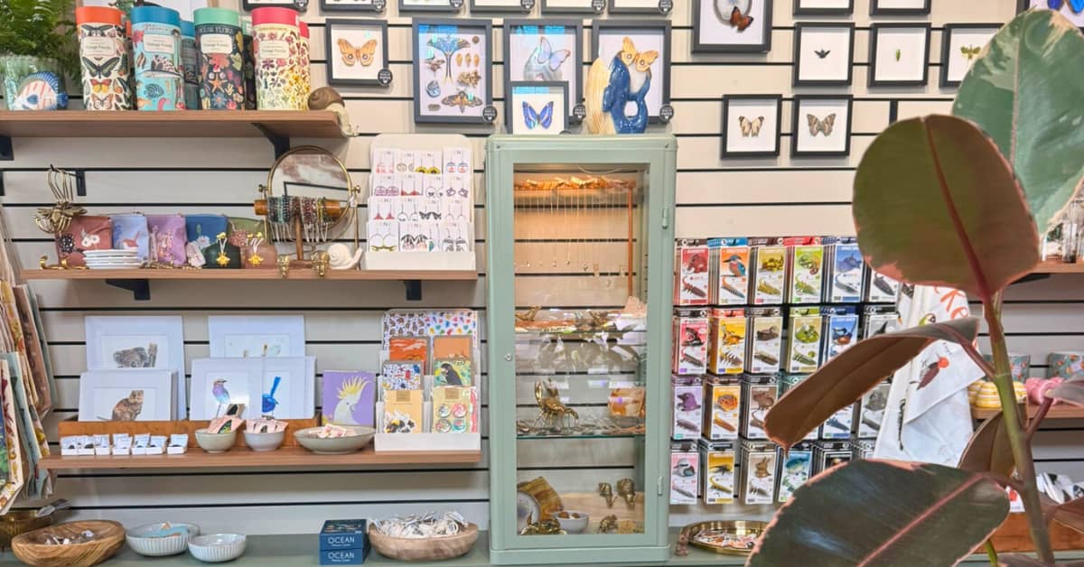 Shelves in a store lined with wildlife-themed gifts like cards and frames and tea towels.