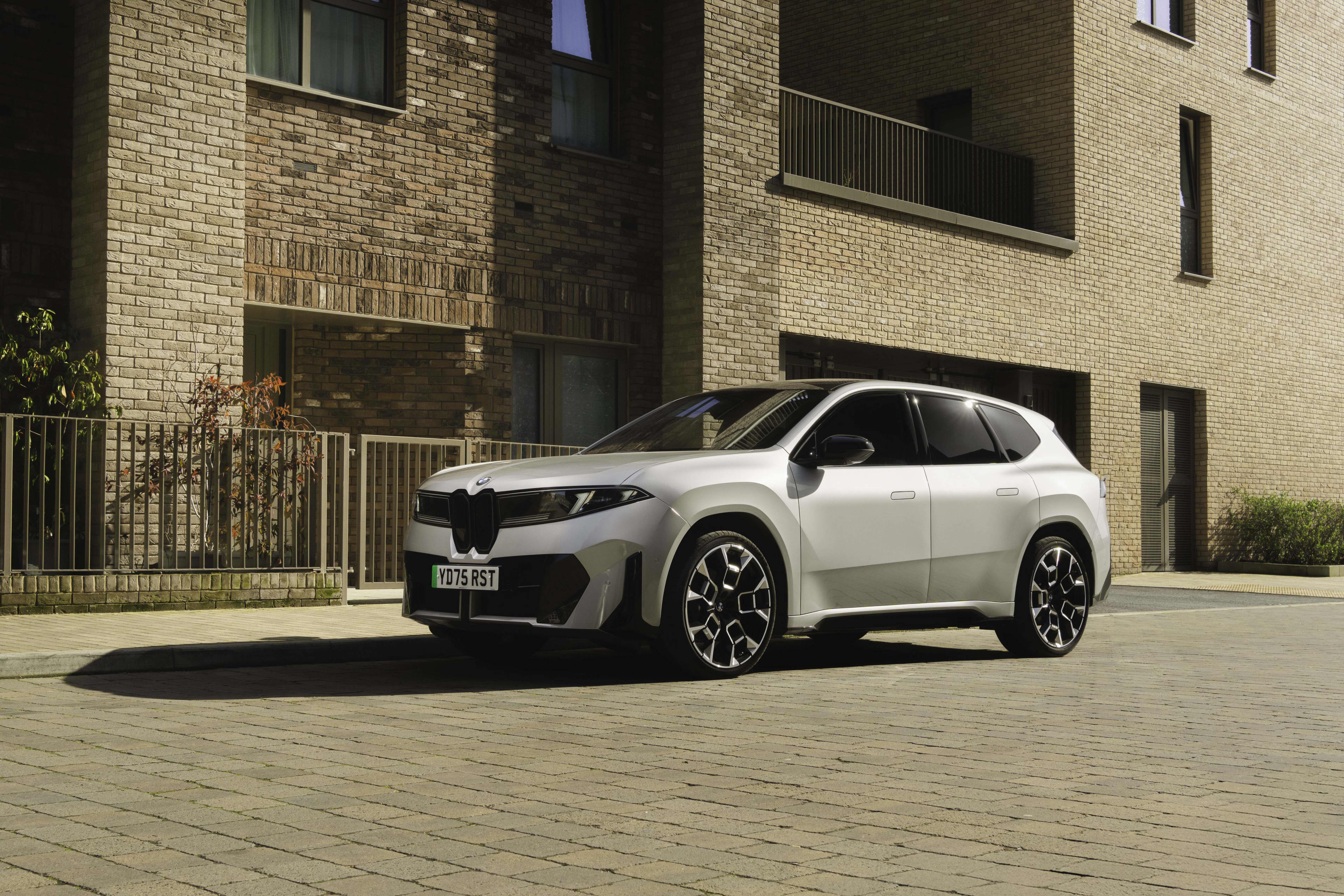 A white BMW ix3 50 xdrive parked in front of a residential building