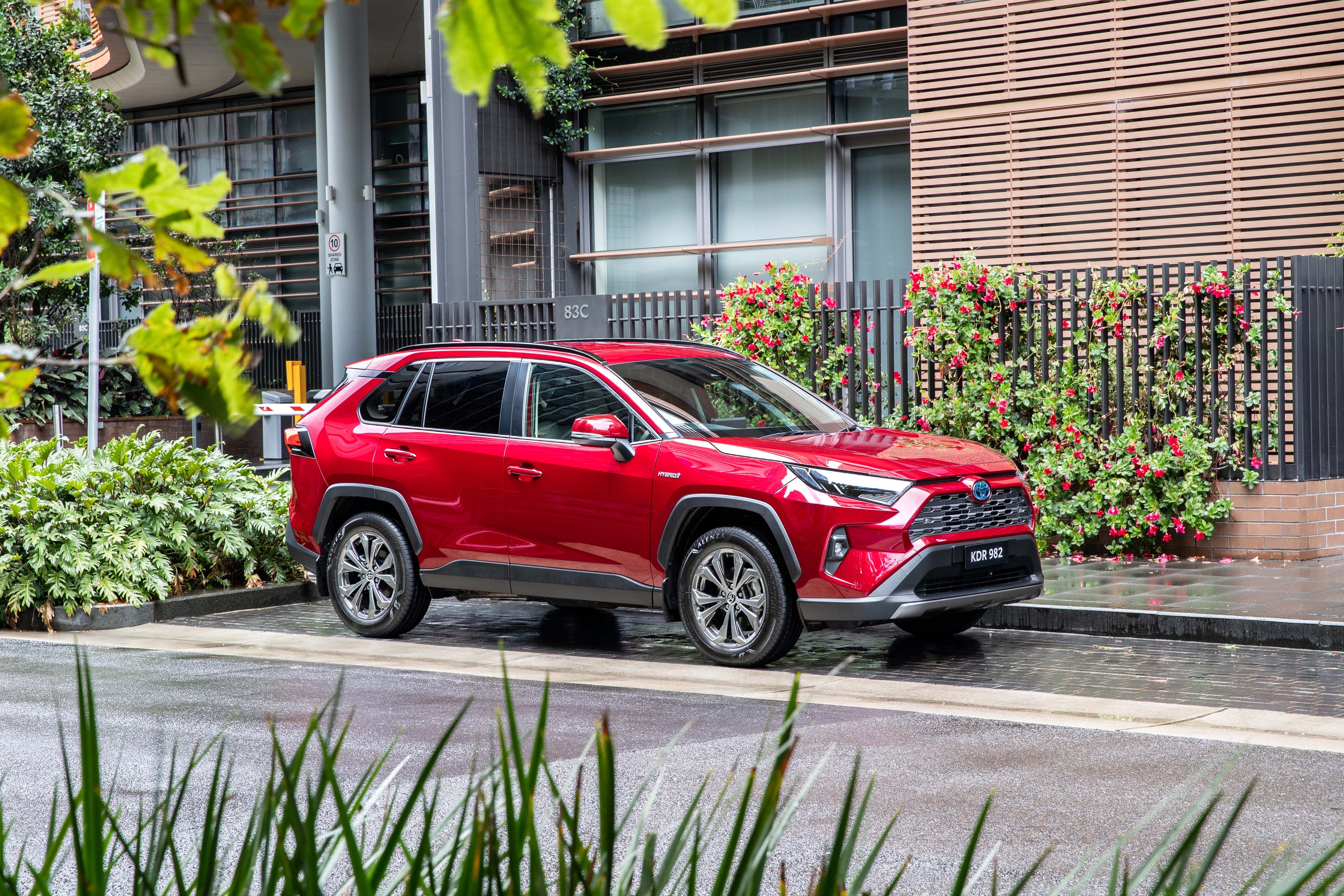A red Toyota RAV4 hybrid parked on a city street