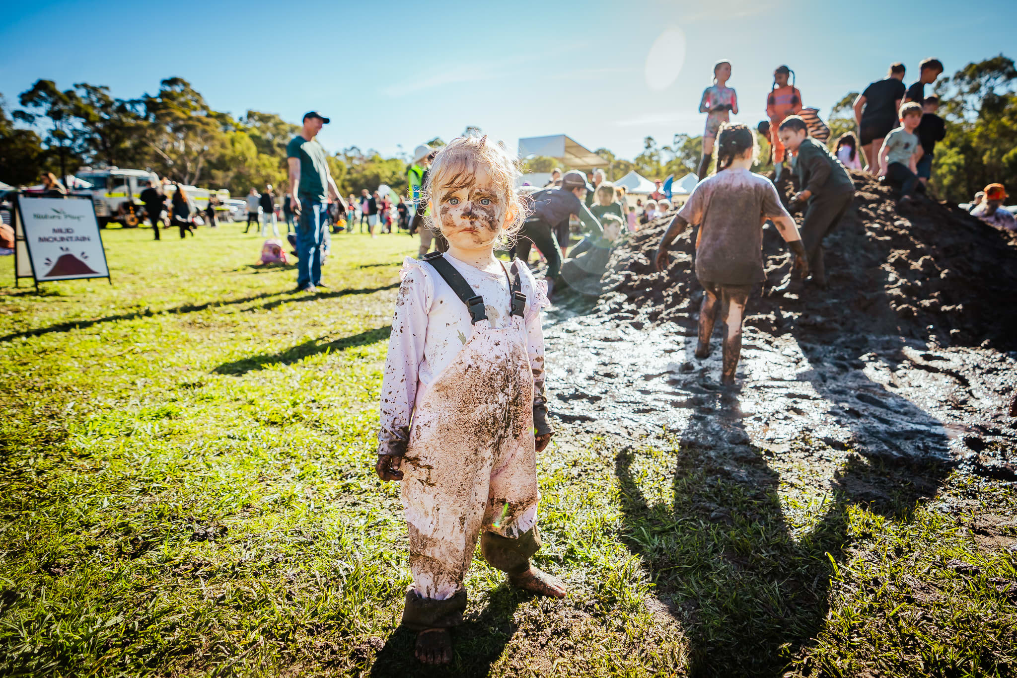 Muddy young child at muddy event outdoors.