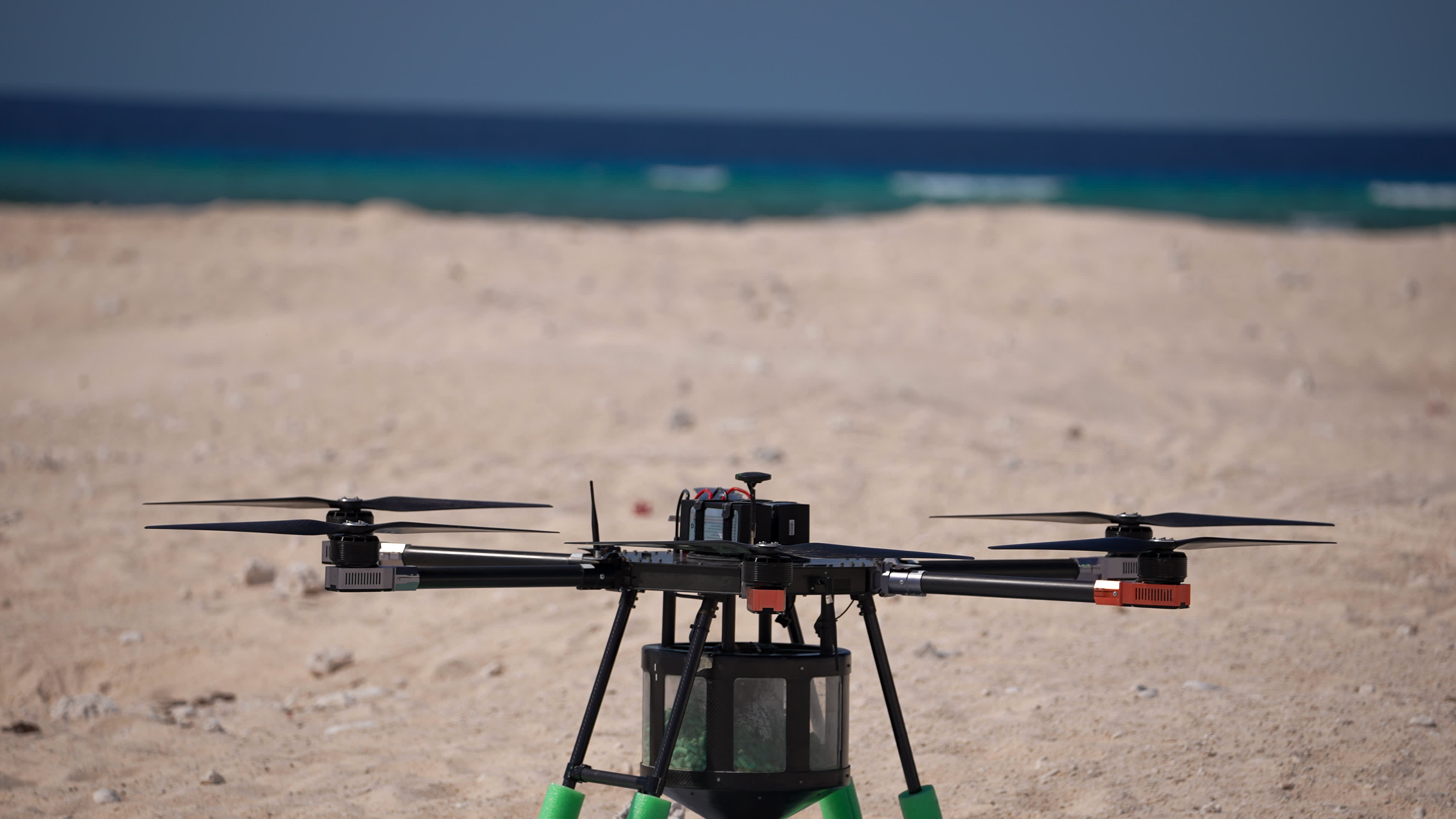A drone sitting on the sand in front of a beach.