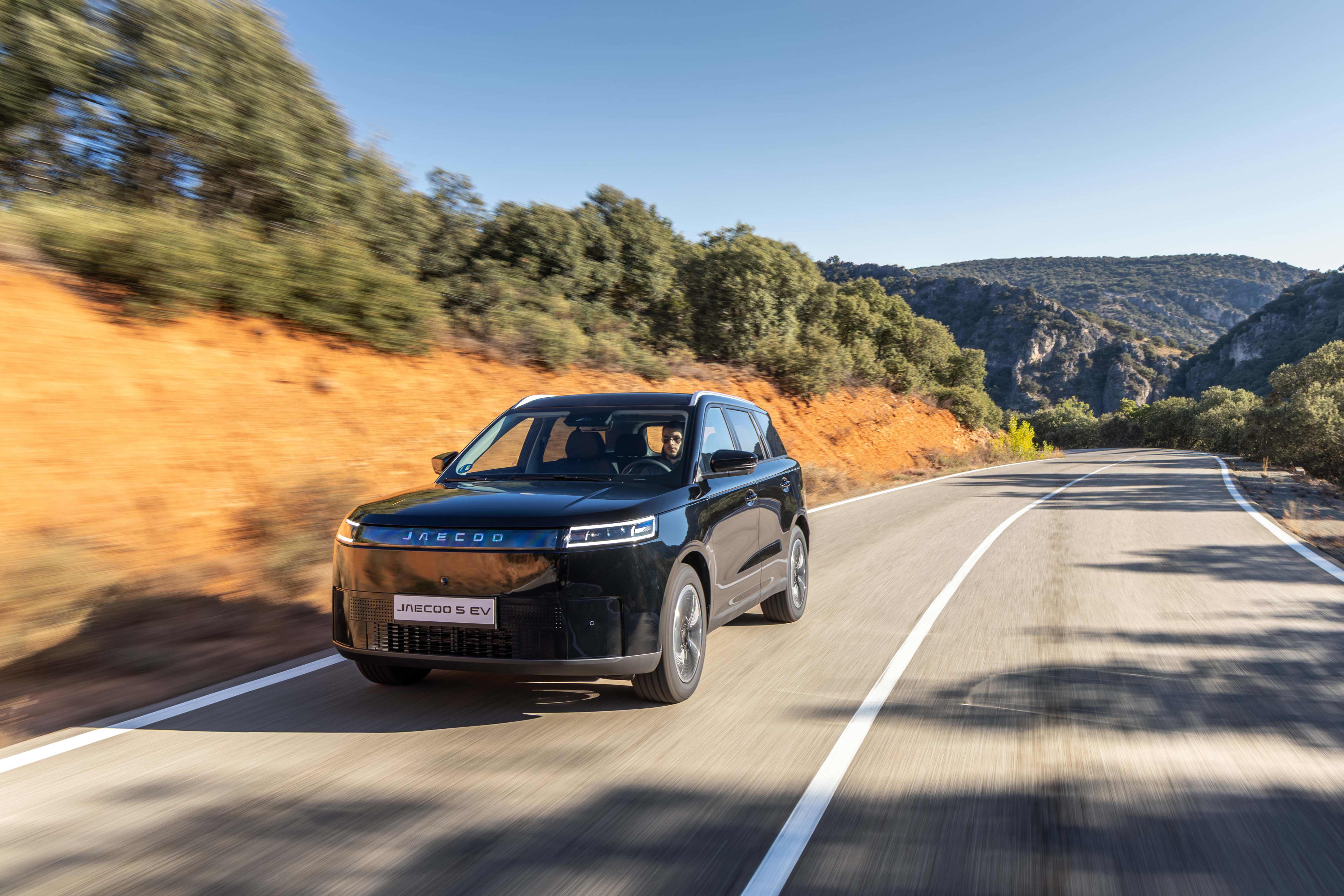 A black Jaecoo 5 EV driving on a country road