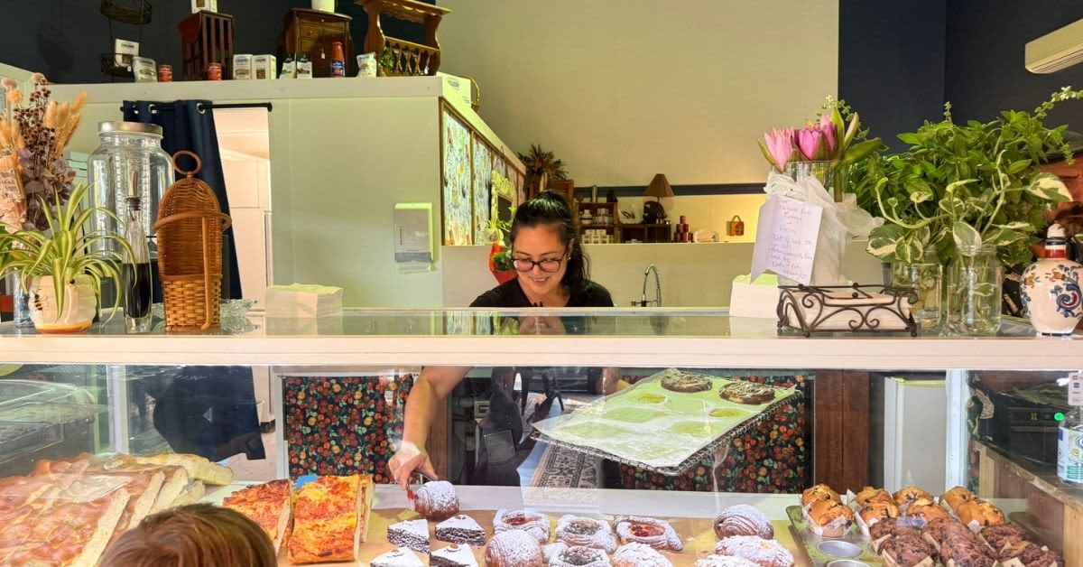 Owner serving up pastries from bakery to family in bakery window.