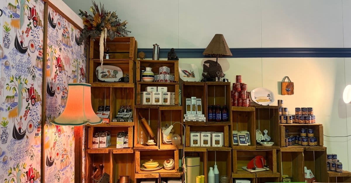 A vintage floor lamp and seating with shelves of Italian pantry items in the background.