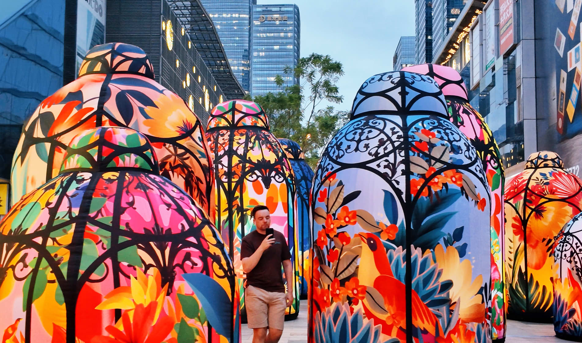 Subi Blooms lanterns outside with city skyline in background.