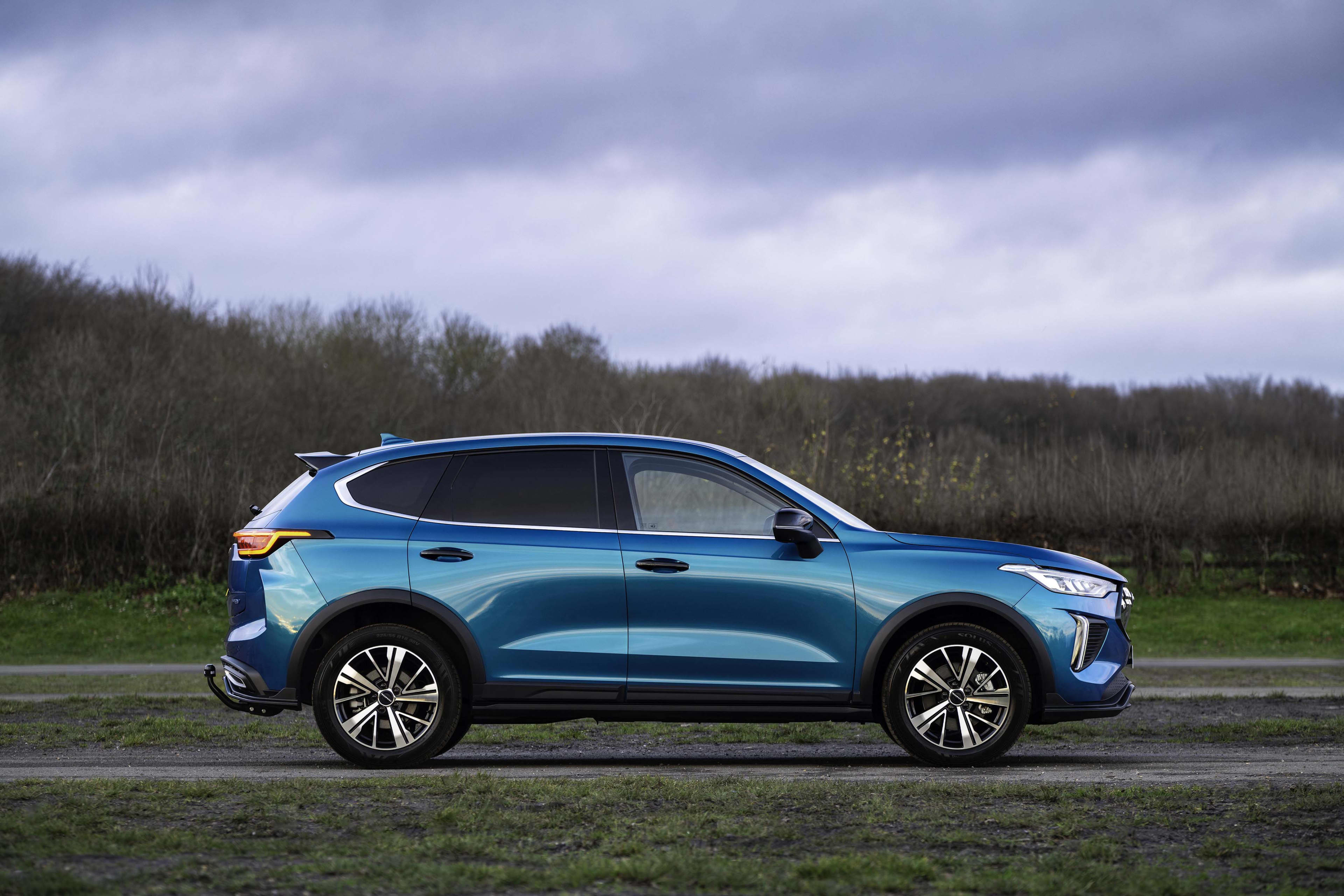 A silver blue GWM Haval Jolion pro hybrid driving on a country road