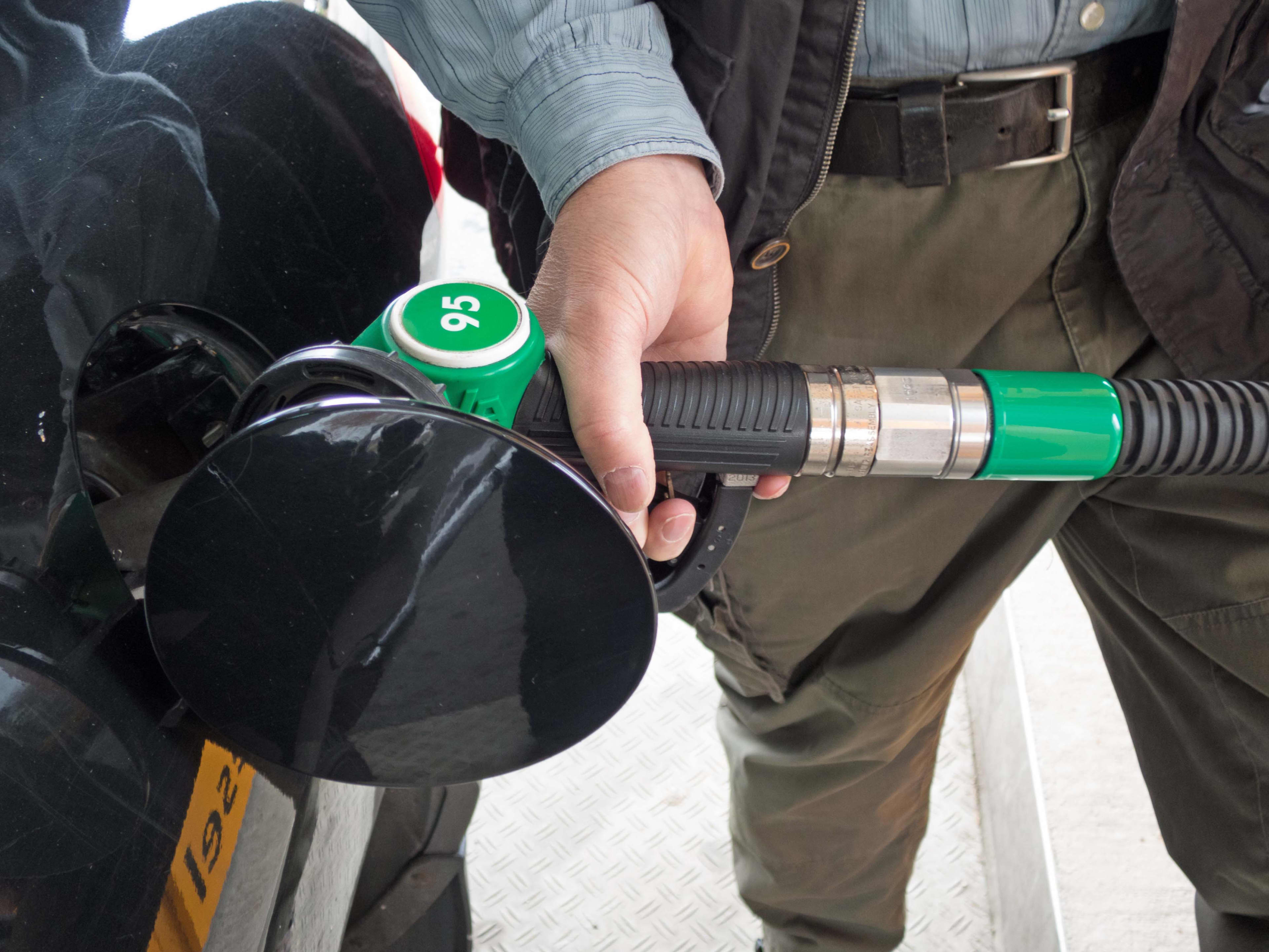 A close up of a person pumping 95 RON fuel into their car