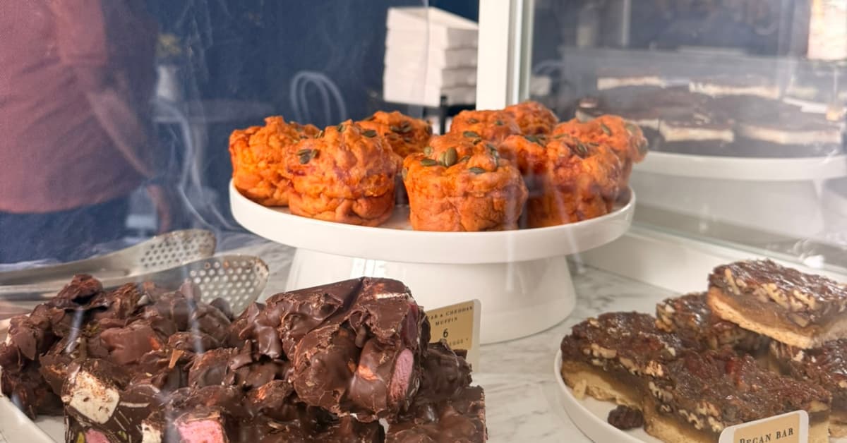 Inside a cafe cabinet showing savoury muffins and rocky road