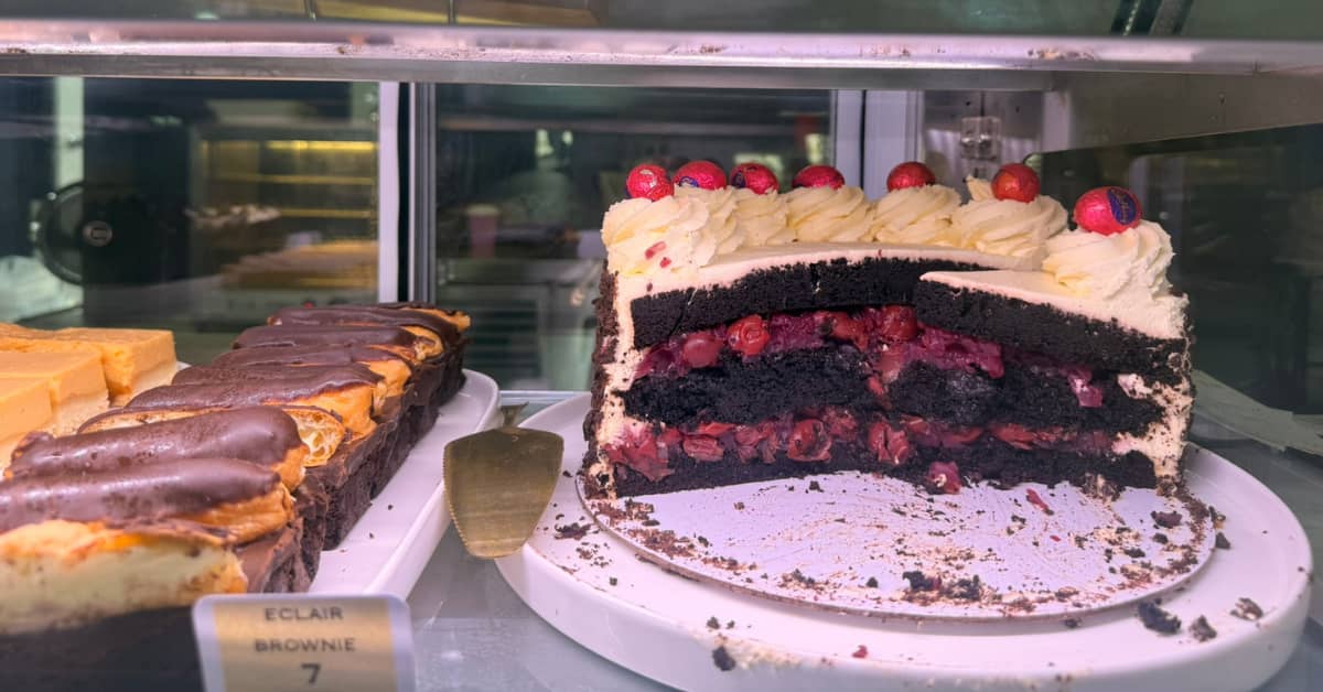 Half eaten black forest cake in cake window in cafe
