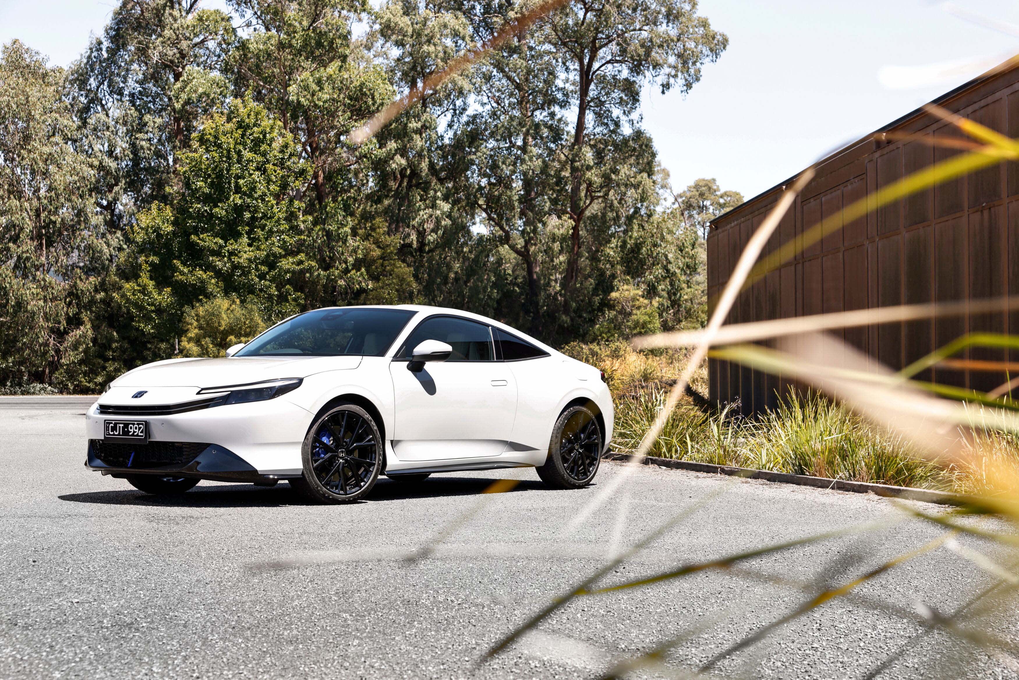 A white Honda Prelude parked outside a modern home
