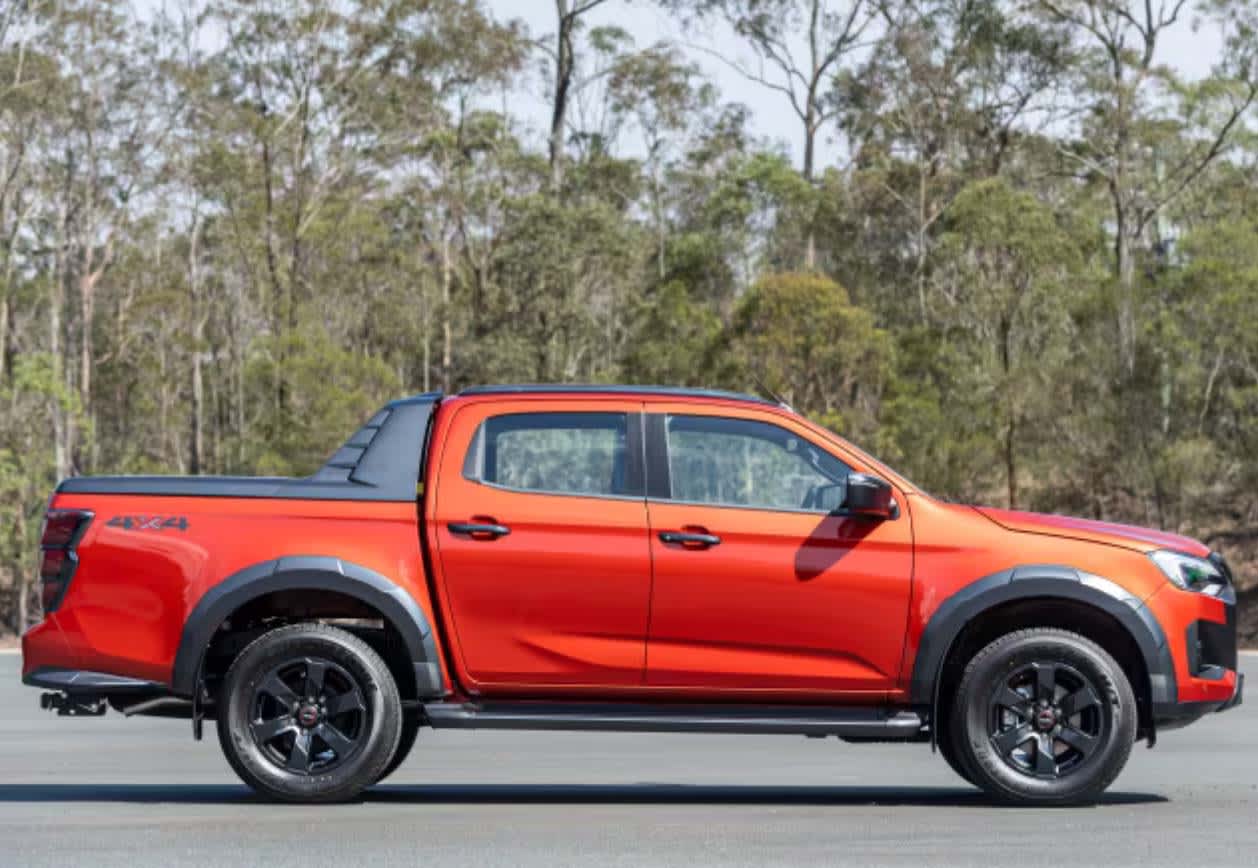 A red Isuzu D-Max 3.0L driving on a country road