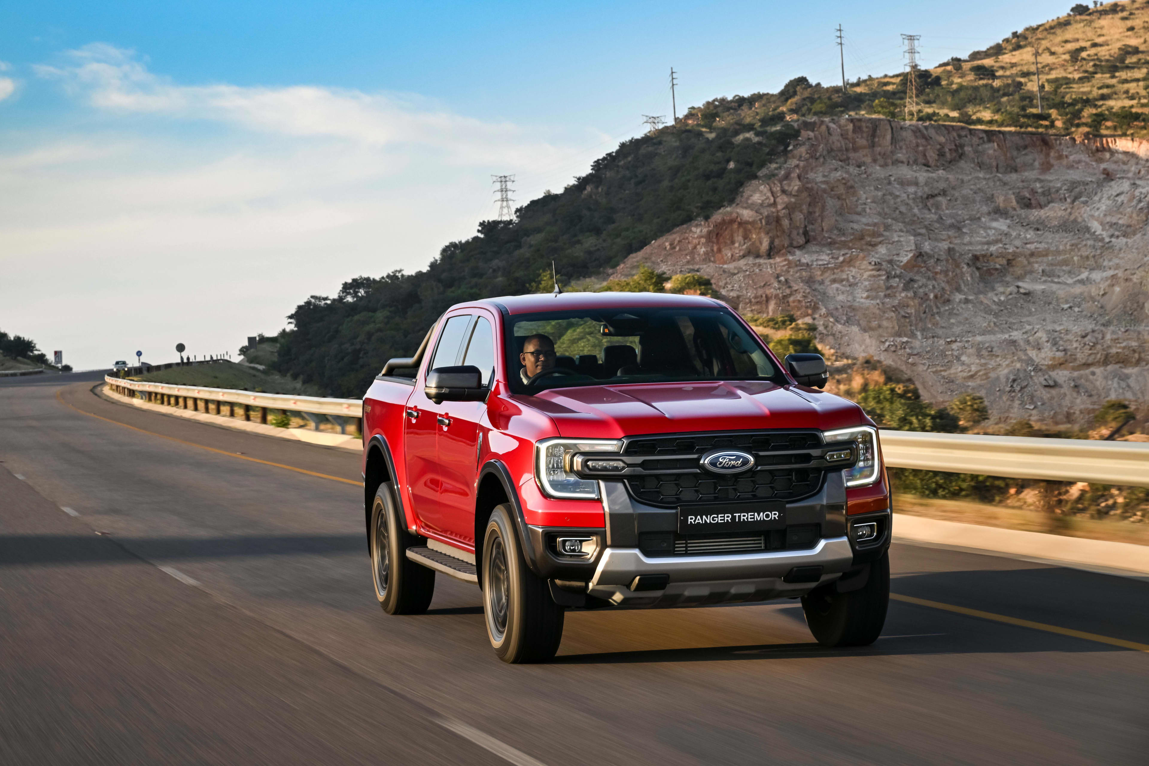 A red Ford Ranger driving on a rural highway