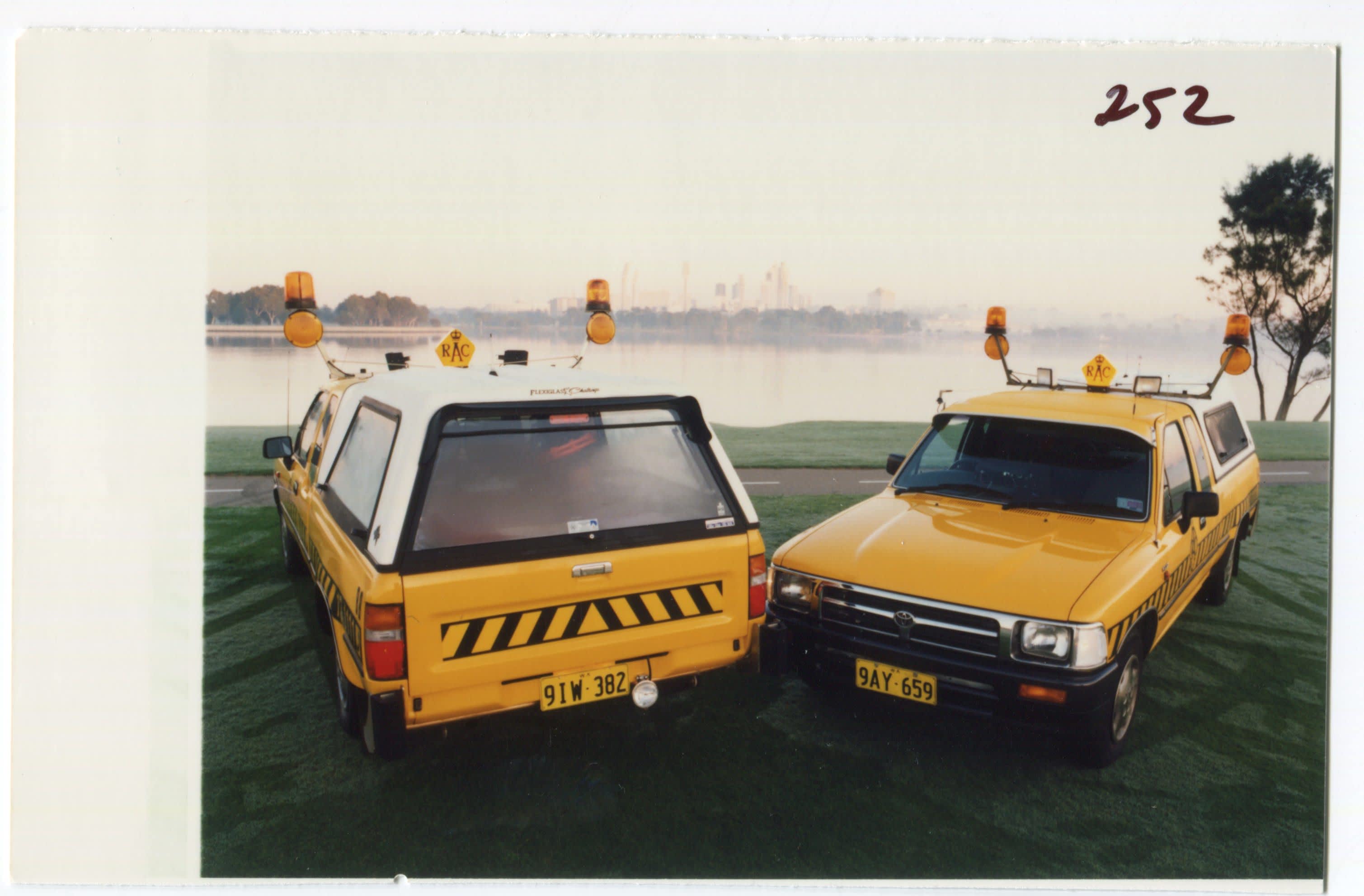 Two yellow RAC Toyota Hilux patrol cars parked on a grassed area